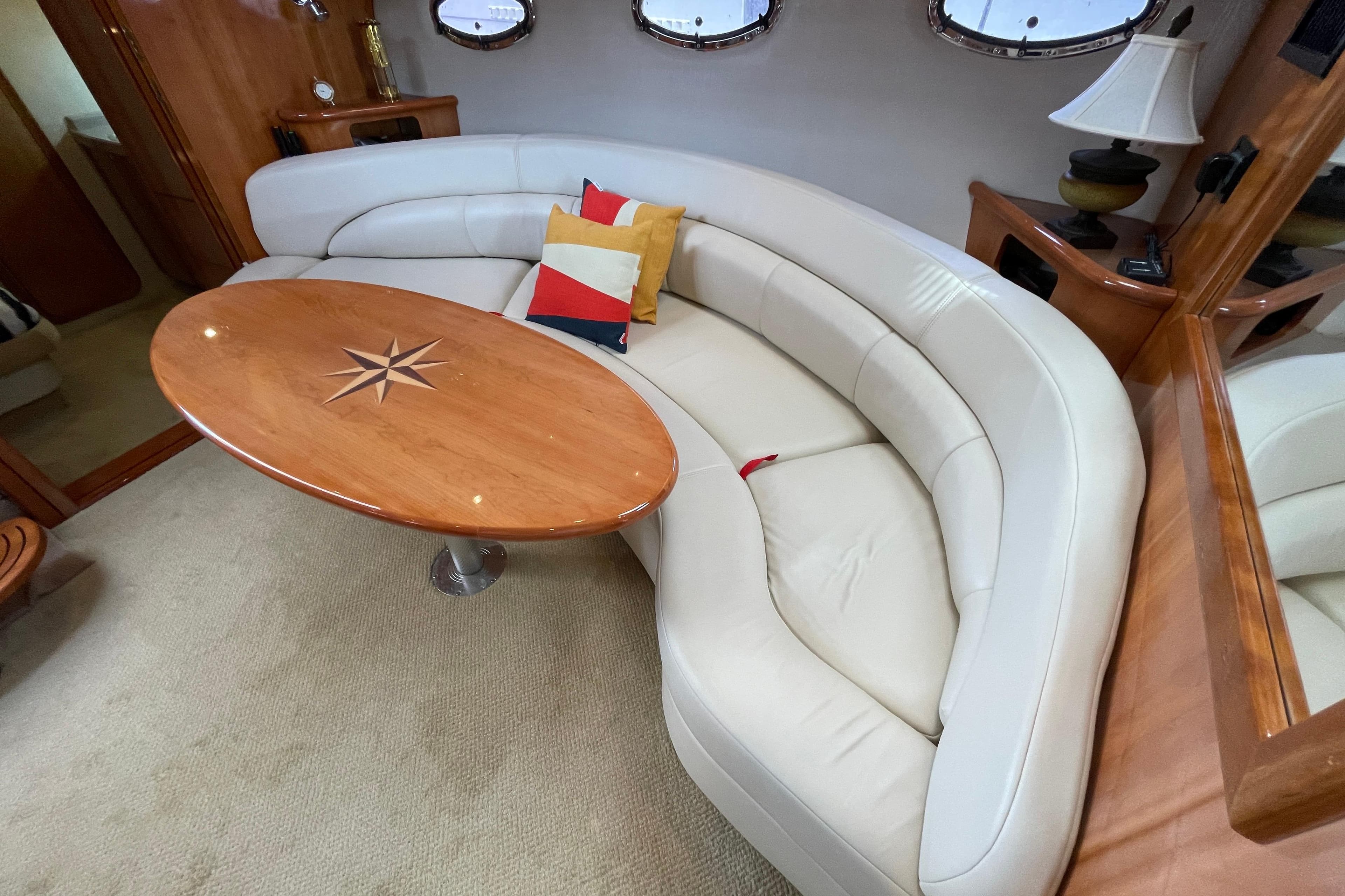 Luxurious interior of 2004 Regal Commodore 4260 yacht with curved seating and wooden table.