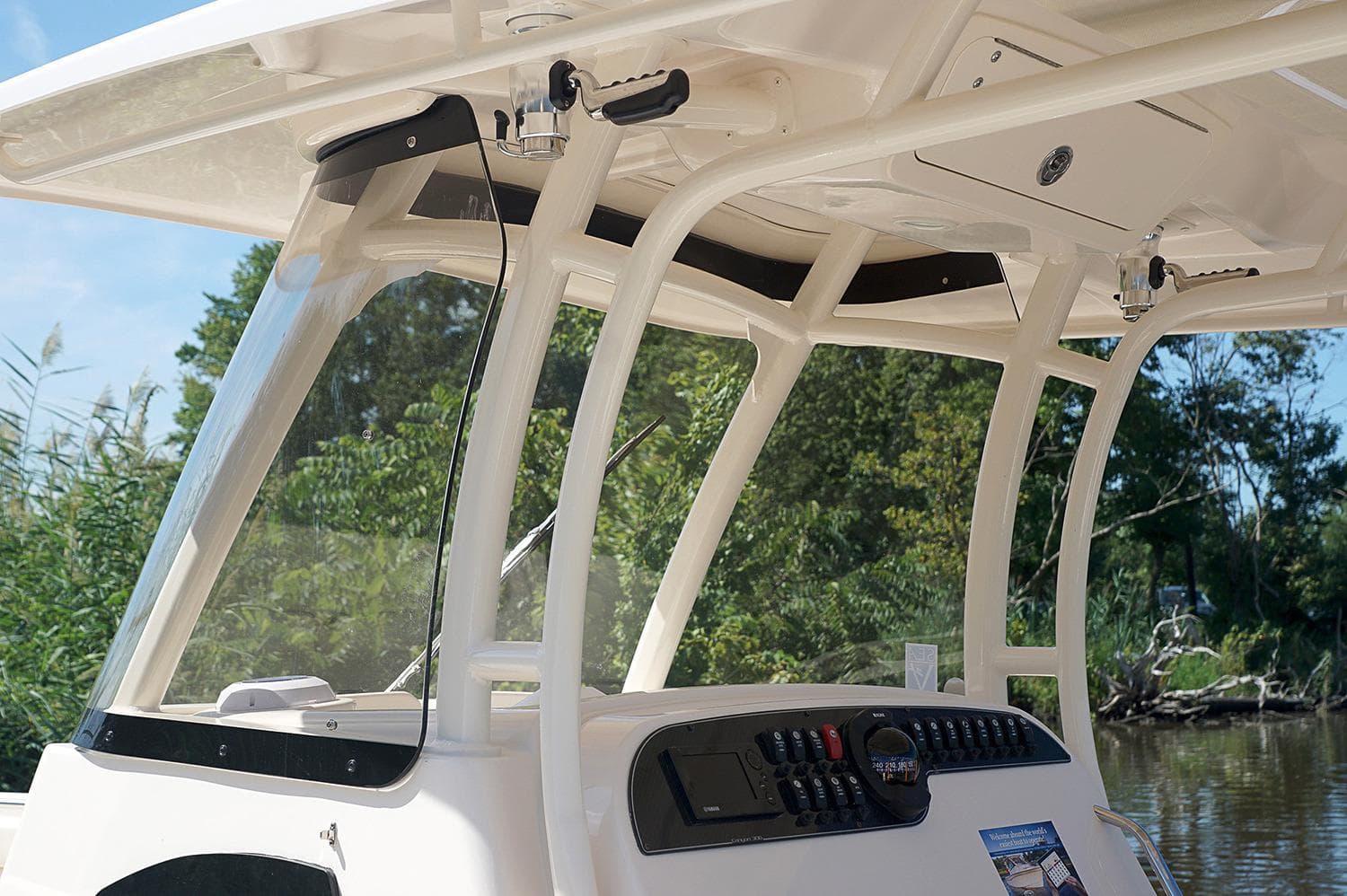 2019 Grady-White Canyon 306 boat console with windshield and controls, surrounded by greenery.