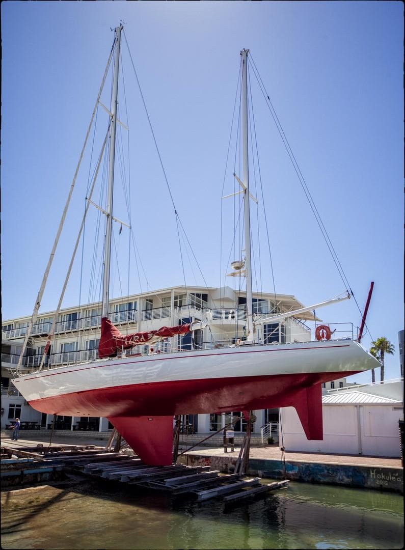 1980 Ketch Presles 72 sailboat on dry dock, with red and white hull.
