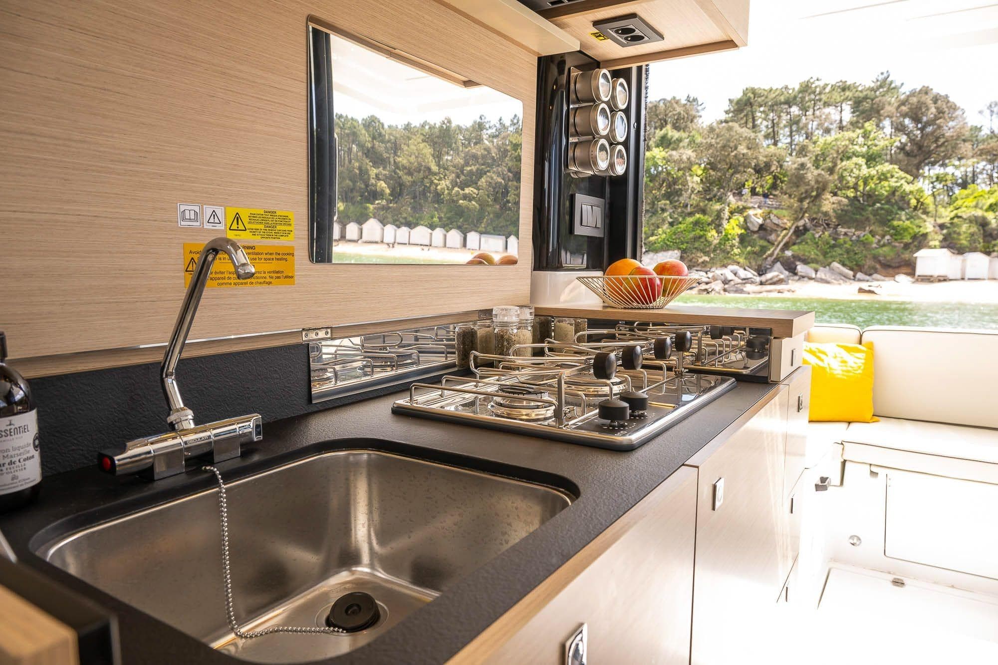 Modern kitchen in 2026 Delphia D10 Sedan yacht with stove, sink, and scenic window view.