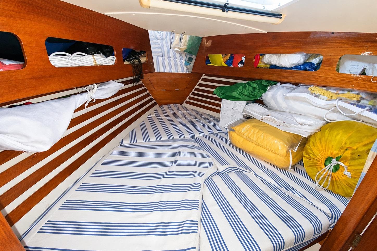 Cozy cabin interior of 1991 Moody 376 sailboat with striped bedding and storage.