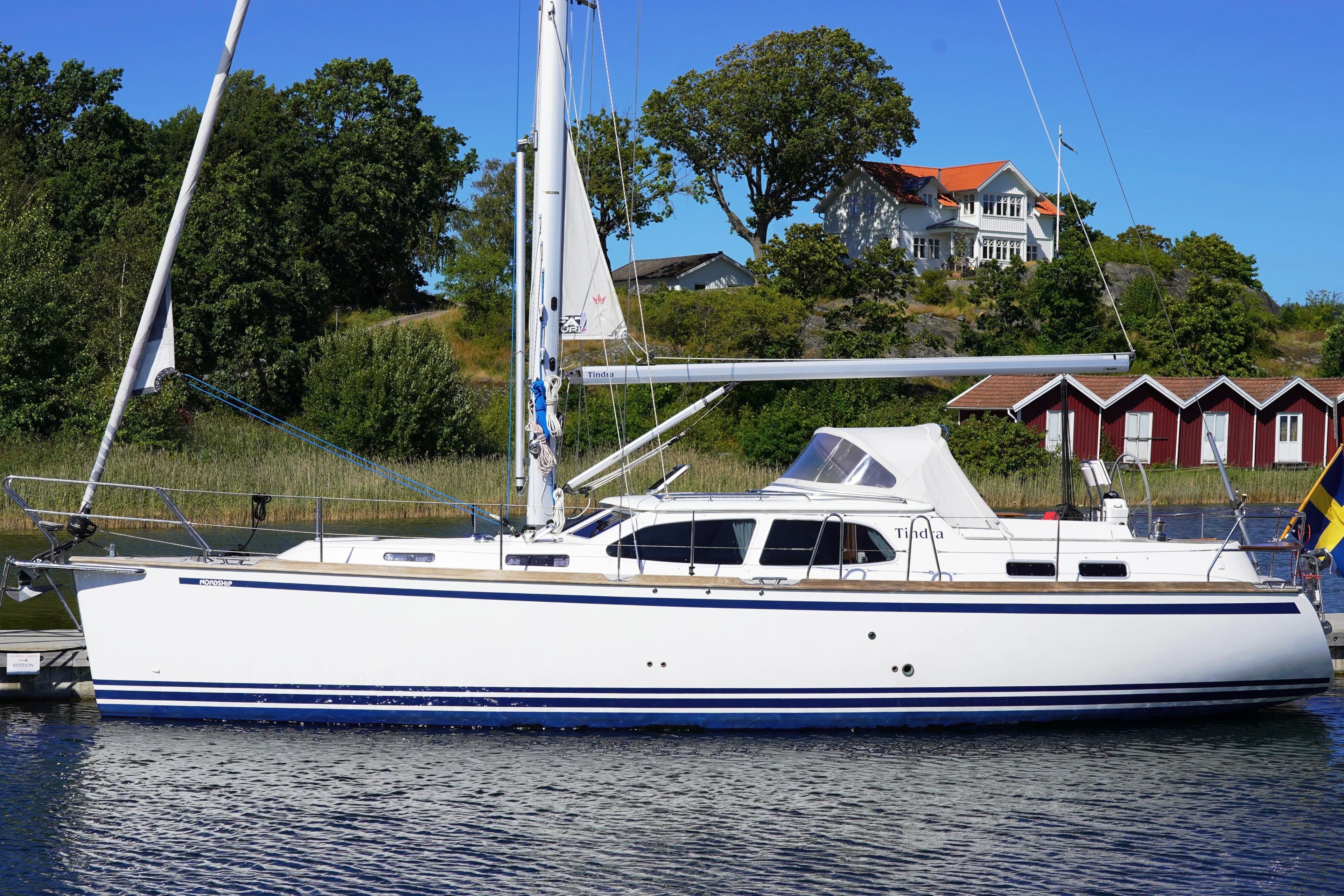 2016 Nordship 380 DS sailboat docked by scenic waterfront homes.