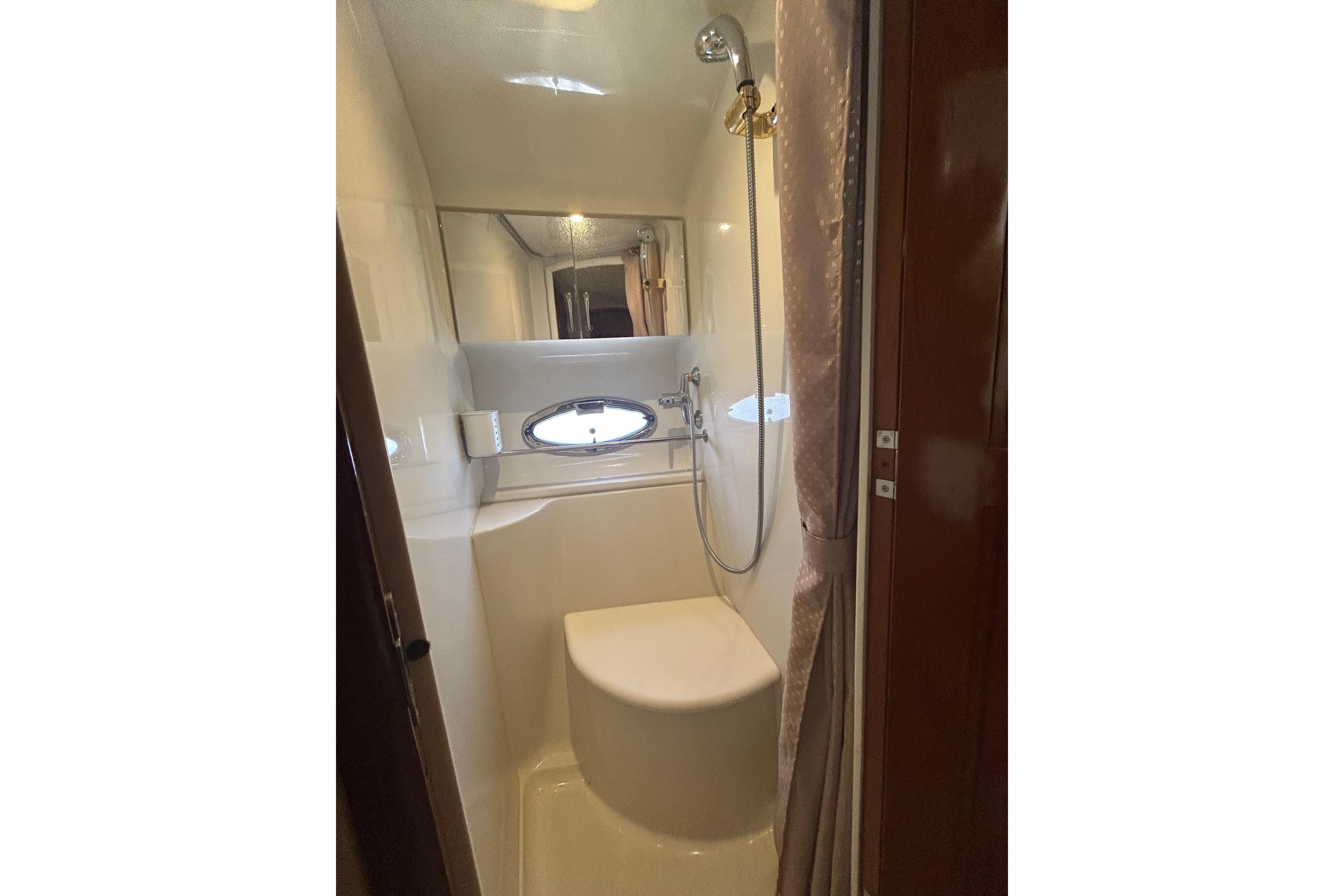 Bathroom interior of 2003 Carver 444 Cockpit Motor Yacht with shower and porthole window.
