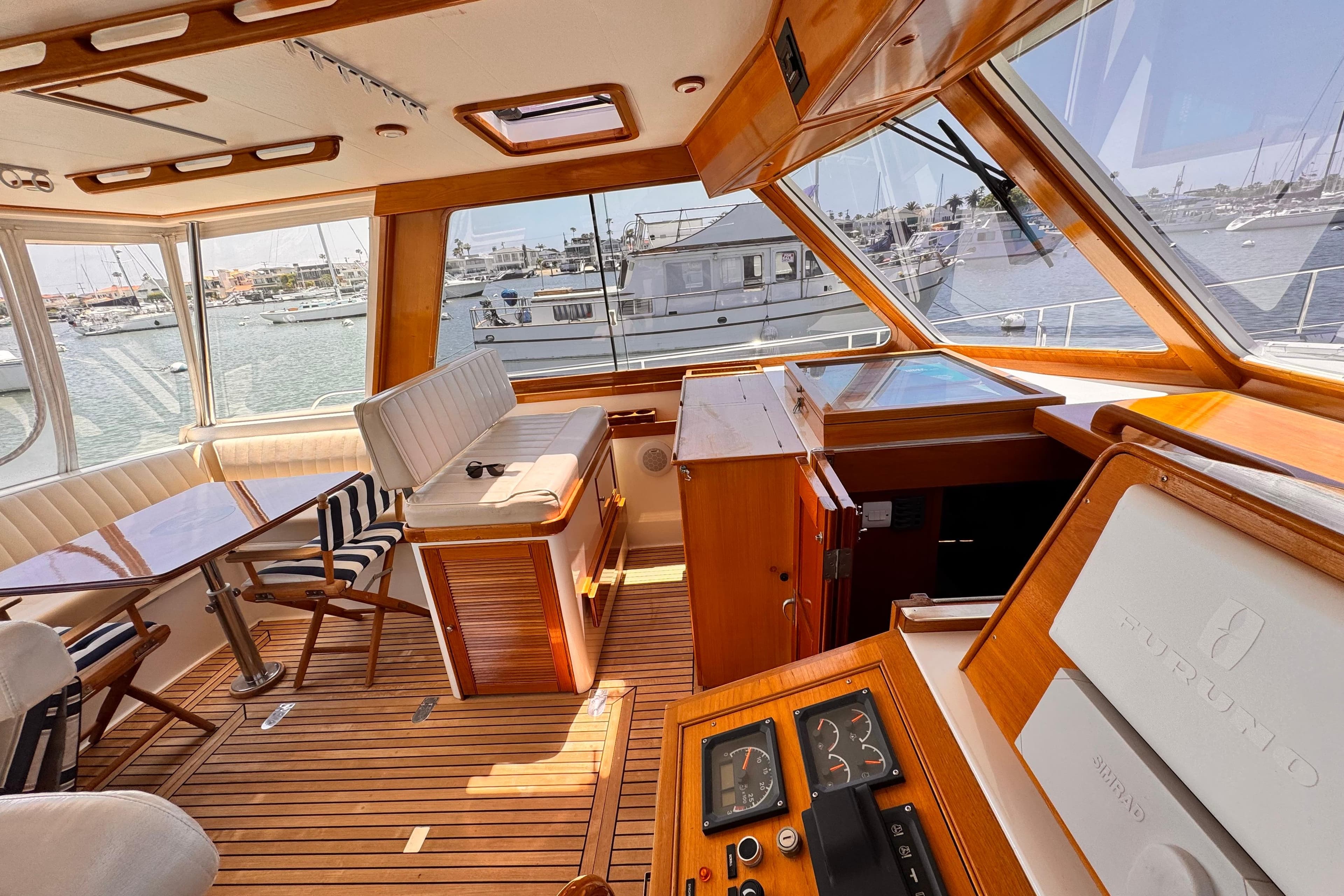 Luxurious interior of 2000 Grand Banks East Bay 49 yacht with wooden finishes and marina view.