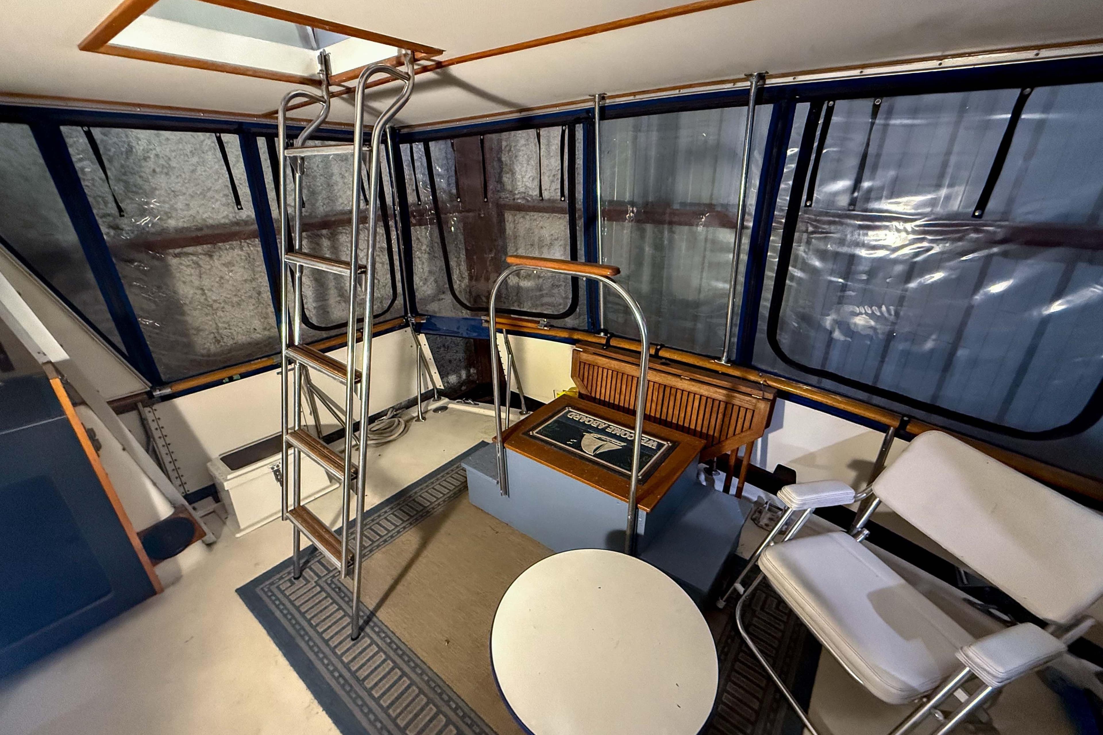 Interior of 1977 Pacemaker FB Motor Yacht with seating, ladder, and windows.