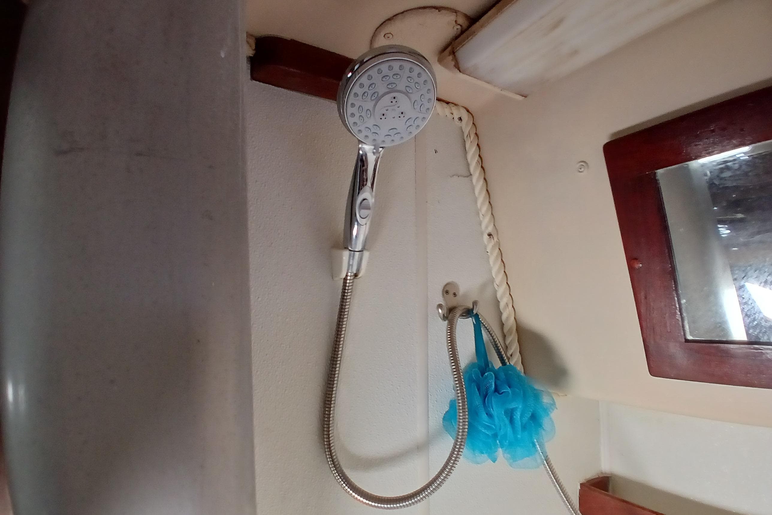 Shower area inside a 1982 Morgan 416 boat, featuring a handheld showerhead and blue bath sponge.
