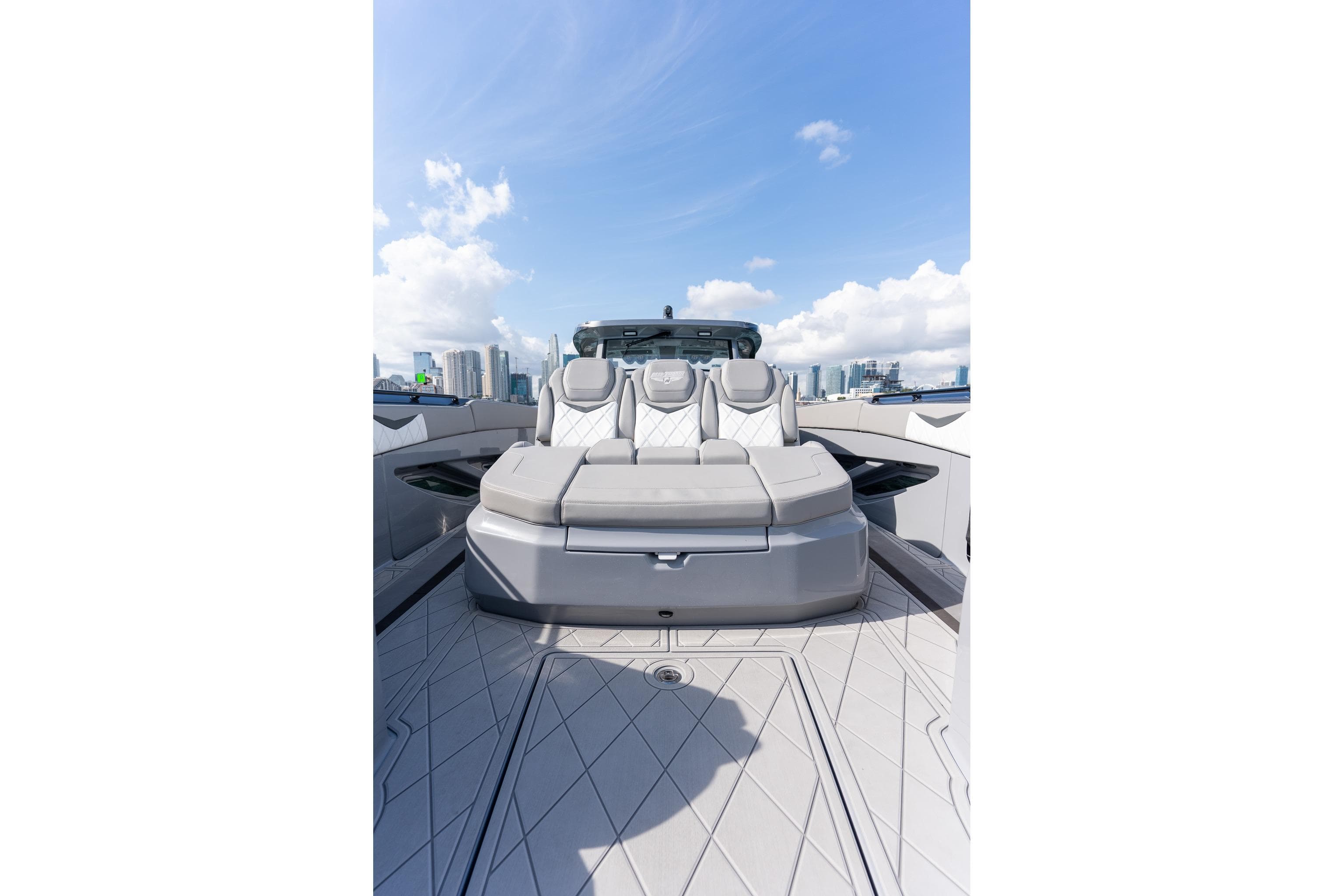 2026 Deep Impact 499 Sport luxury boat with sleek seating, city skyline in background.