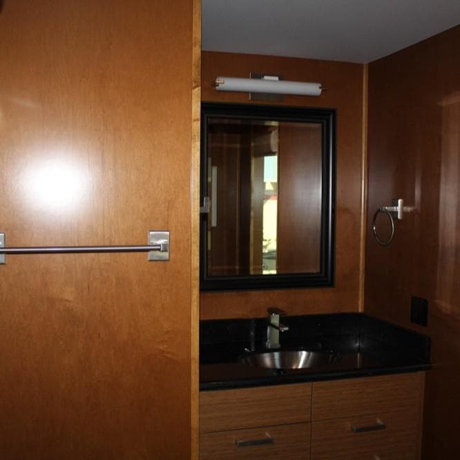Wood-paneled bathroom with mirror and sink in Bravada Intrepid Trip #1, 2015 model.