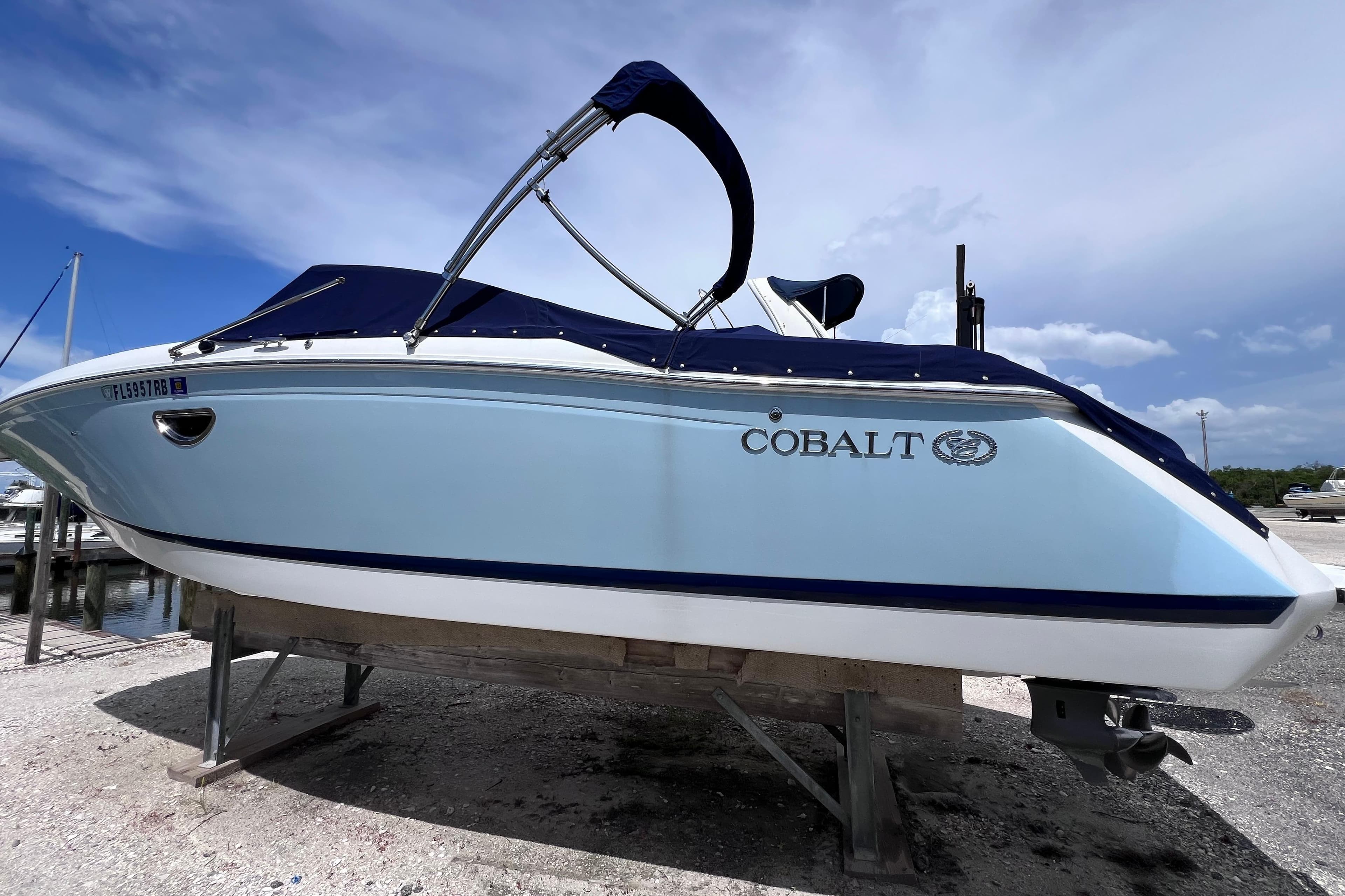 2015 Cobalt 26SD boat with blue cover on a stand, under a clear sky.