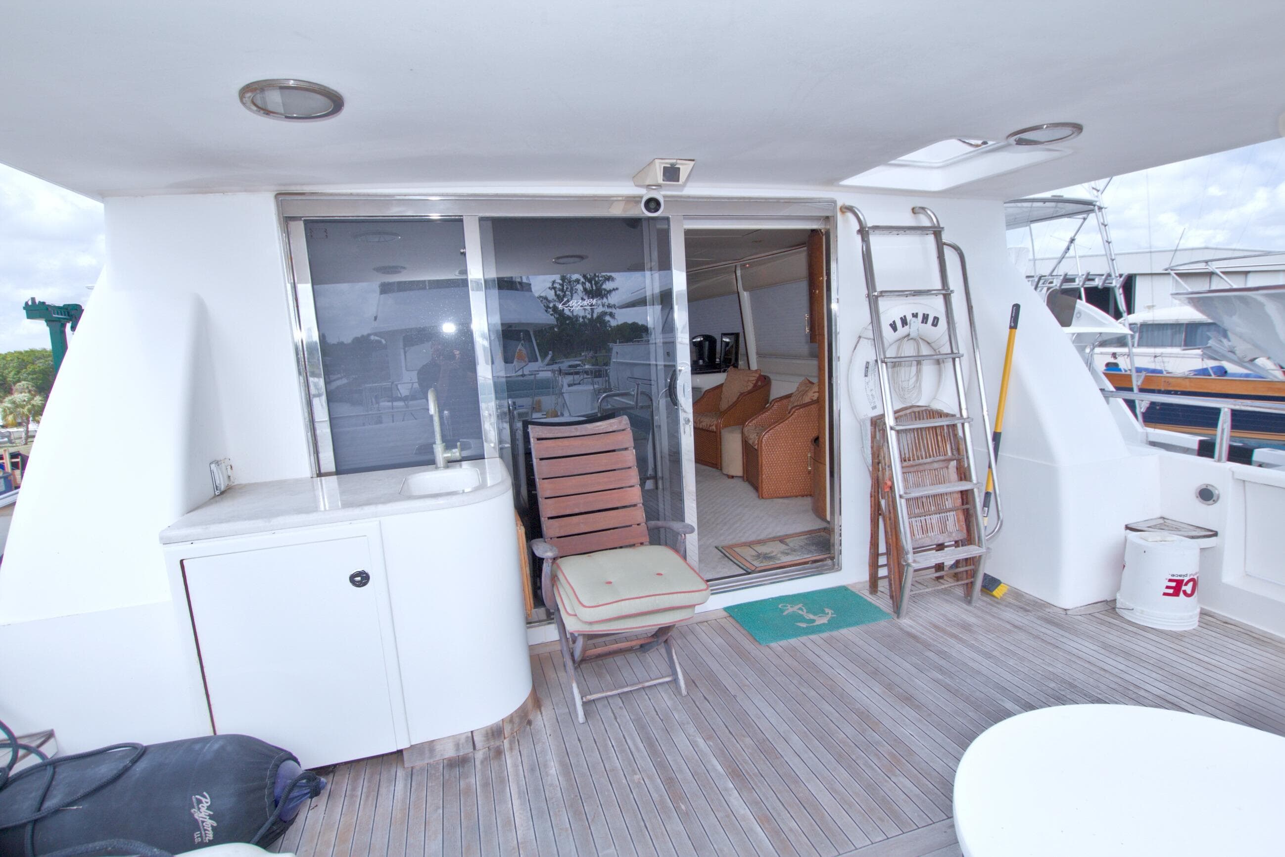 Outdoor deck of 1998 Lazzara 76 Skylounge Grand Salon yacht with seating and ladder.