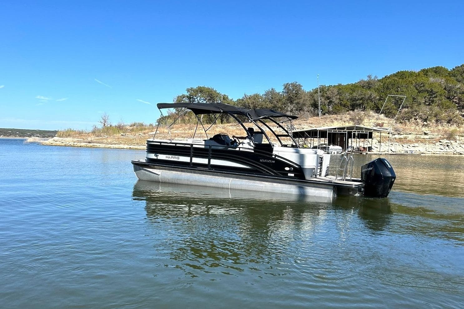 2020 Harris FloteBote Solstice 230 pontoon boat on a serene lake.