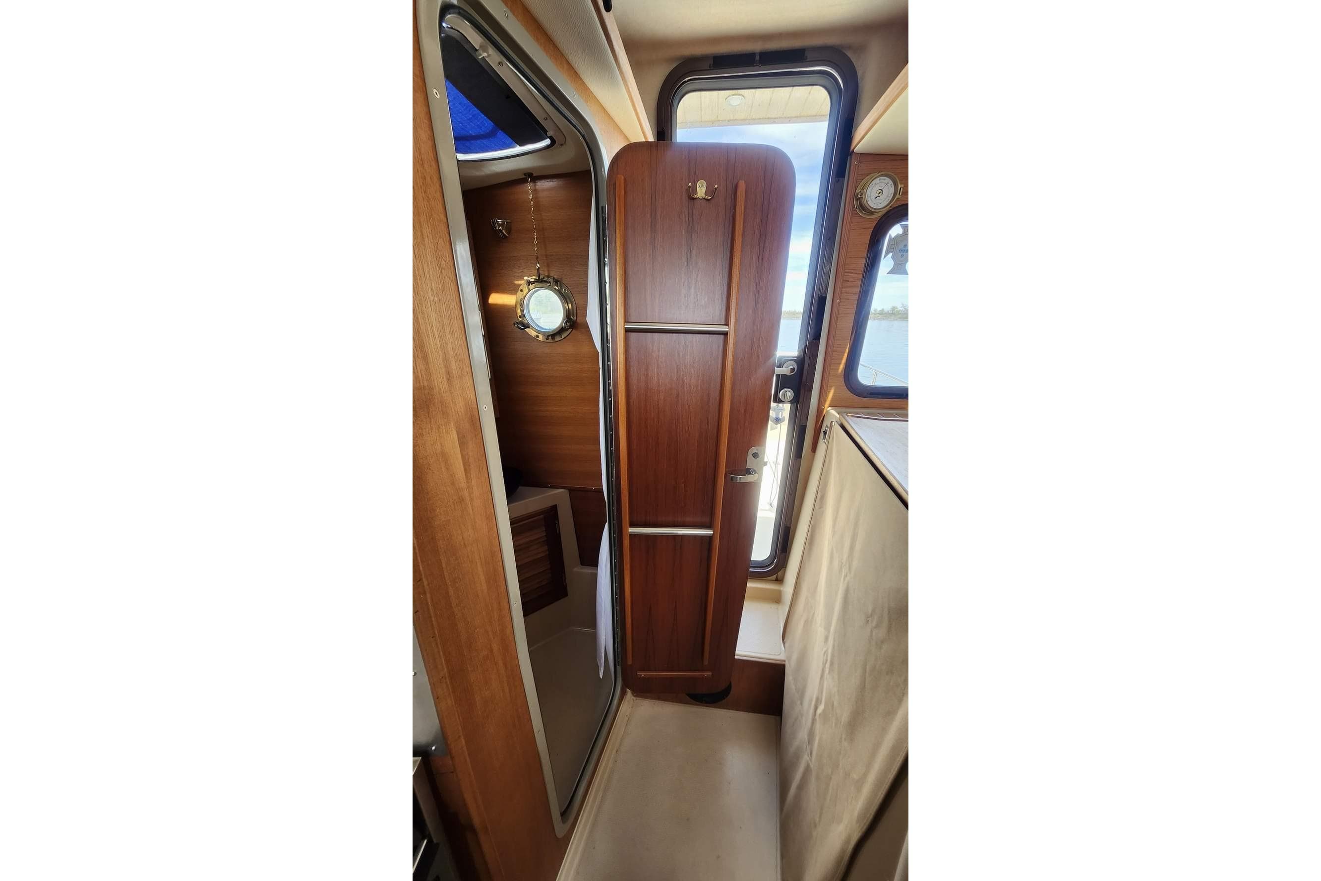 Interior view of 2014 Ranger Tugs R-27 cabin with wooden door and porthole.