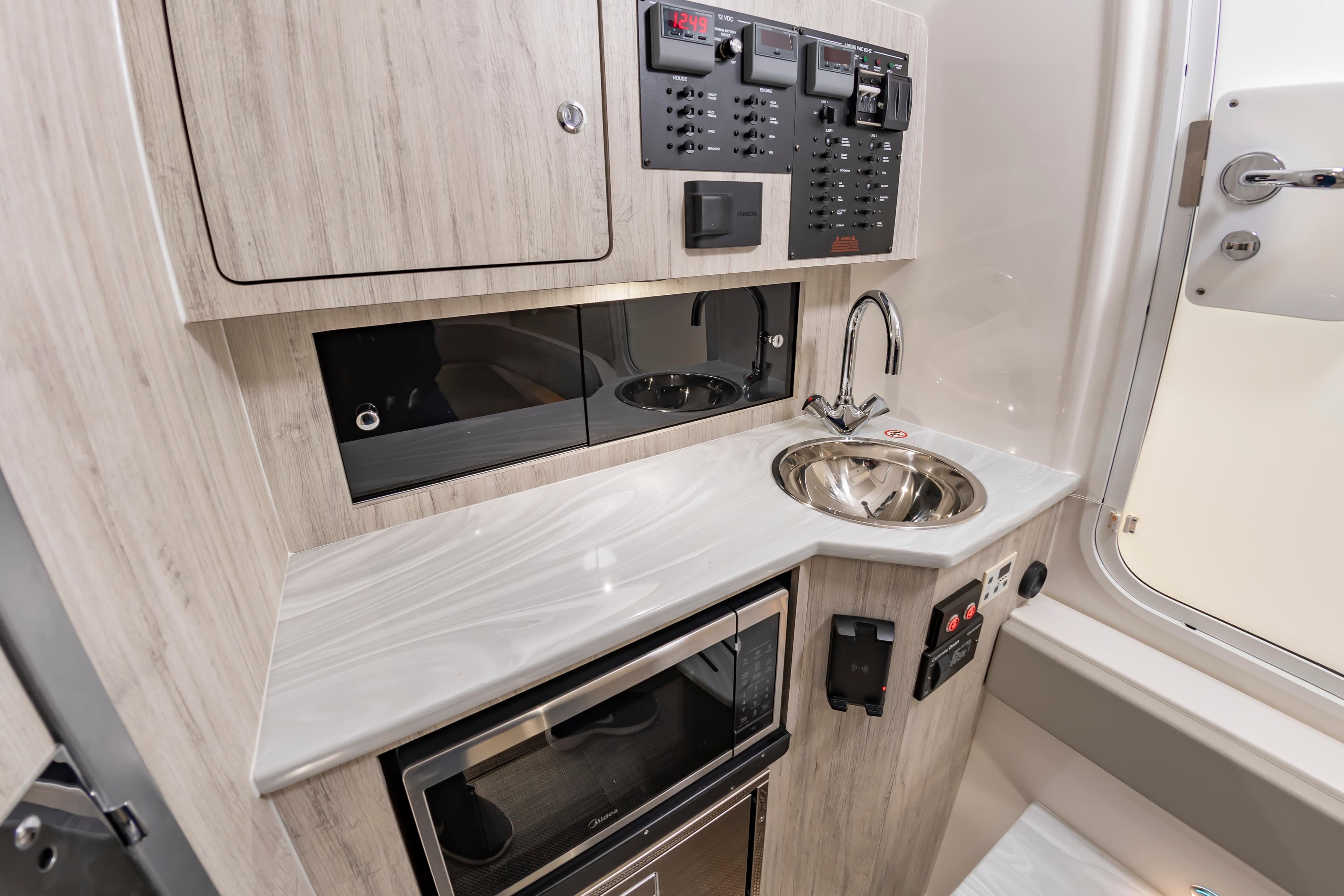 Modern interior of 2026 Regulator 37 boat featuring a compact kitchenette with sink and control panel.
