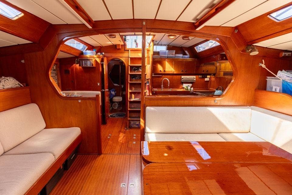 Interior of 1982 Nautor Swan 65 yacht with wooden finishes and cozy seating area.