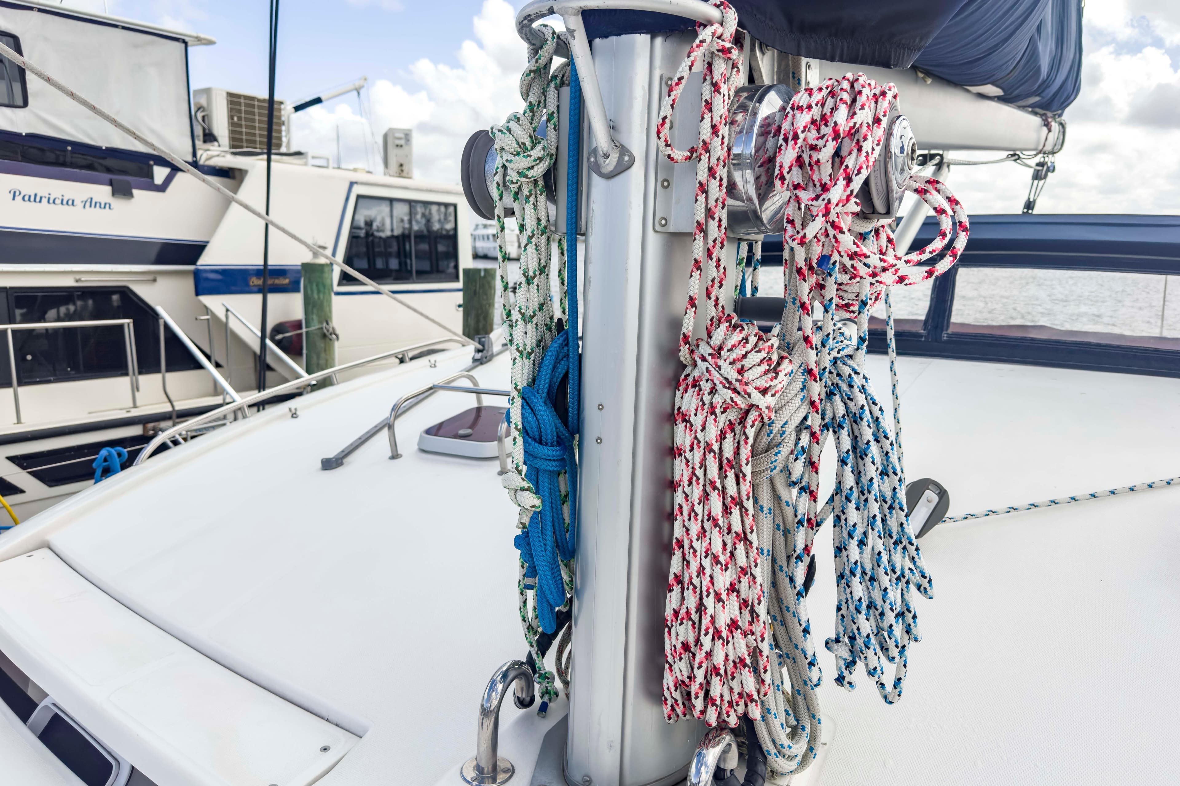 Sailboat deck with colorful ropes, Leopard 42 model, docked near other boats.