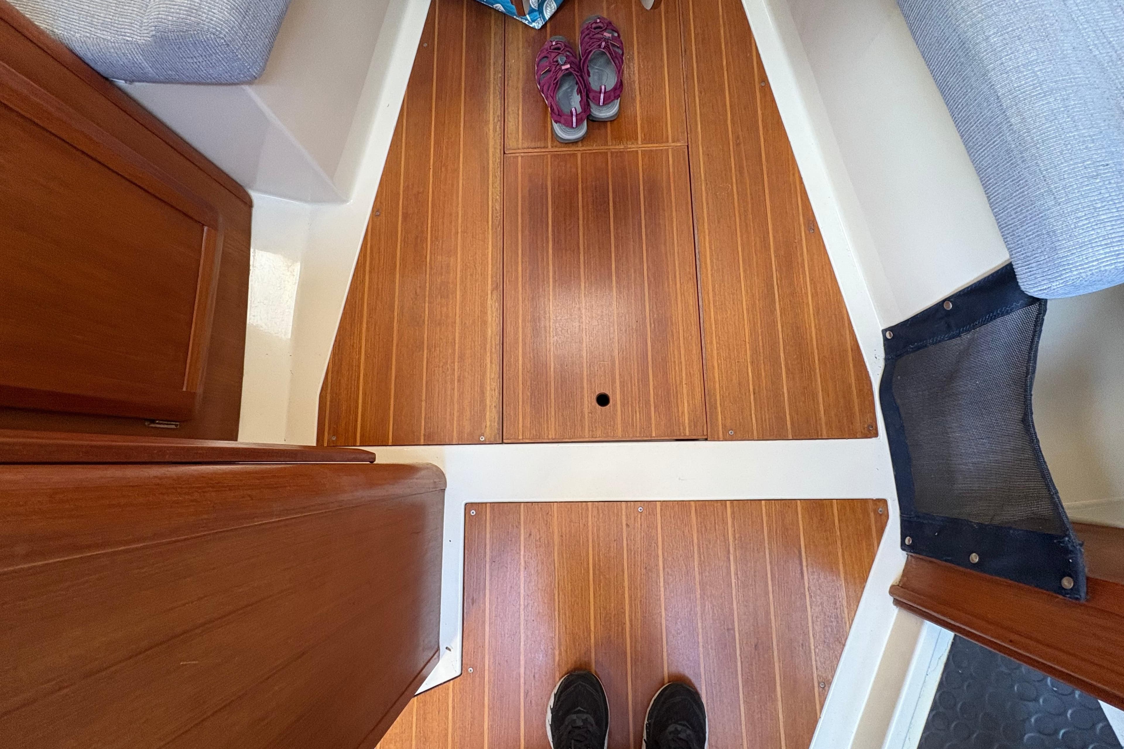 Interior view of a 1993 Hunter 28 sailboat with wooden flooring and visible shoes.