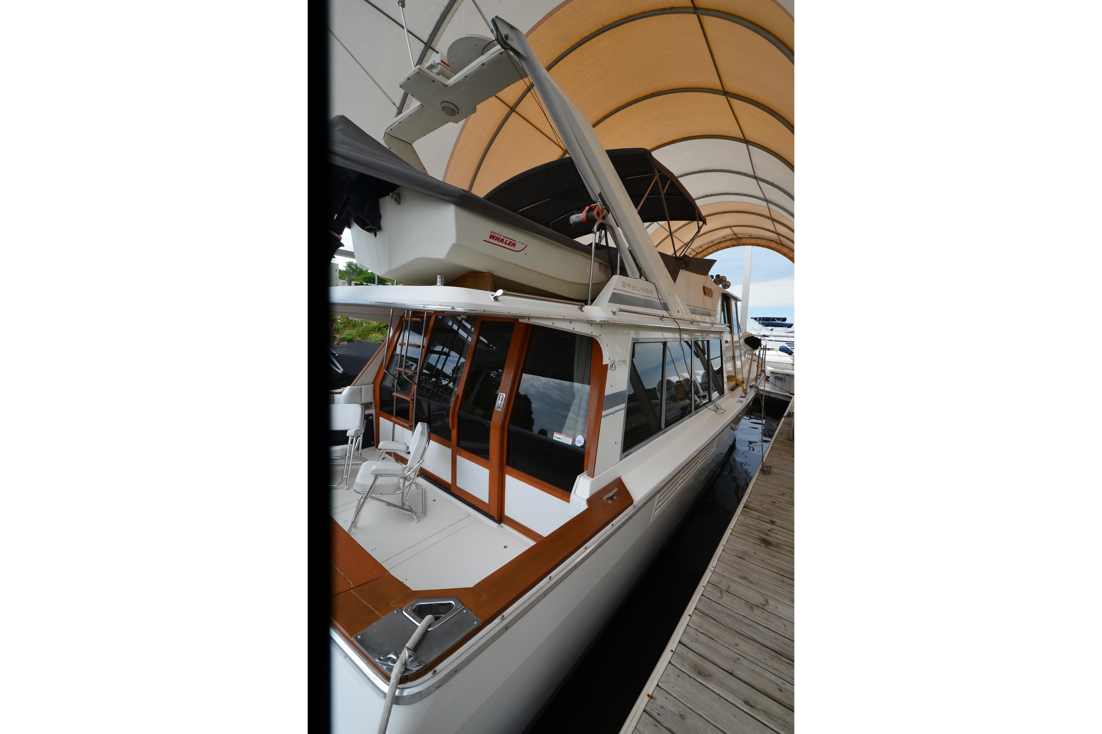 1989 Bayliner 4518 Motoryacht docked under canopy, showcasing sleek design and spacious deck.