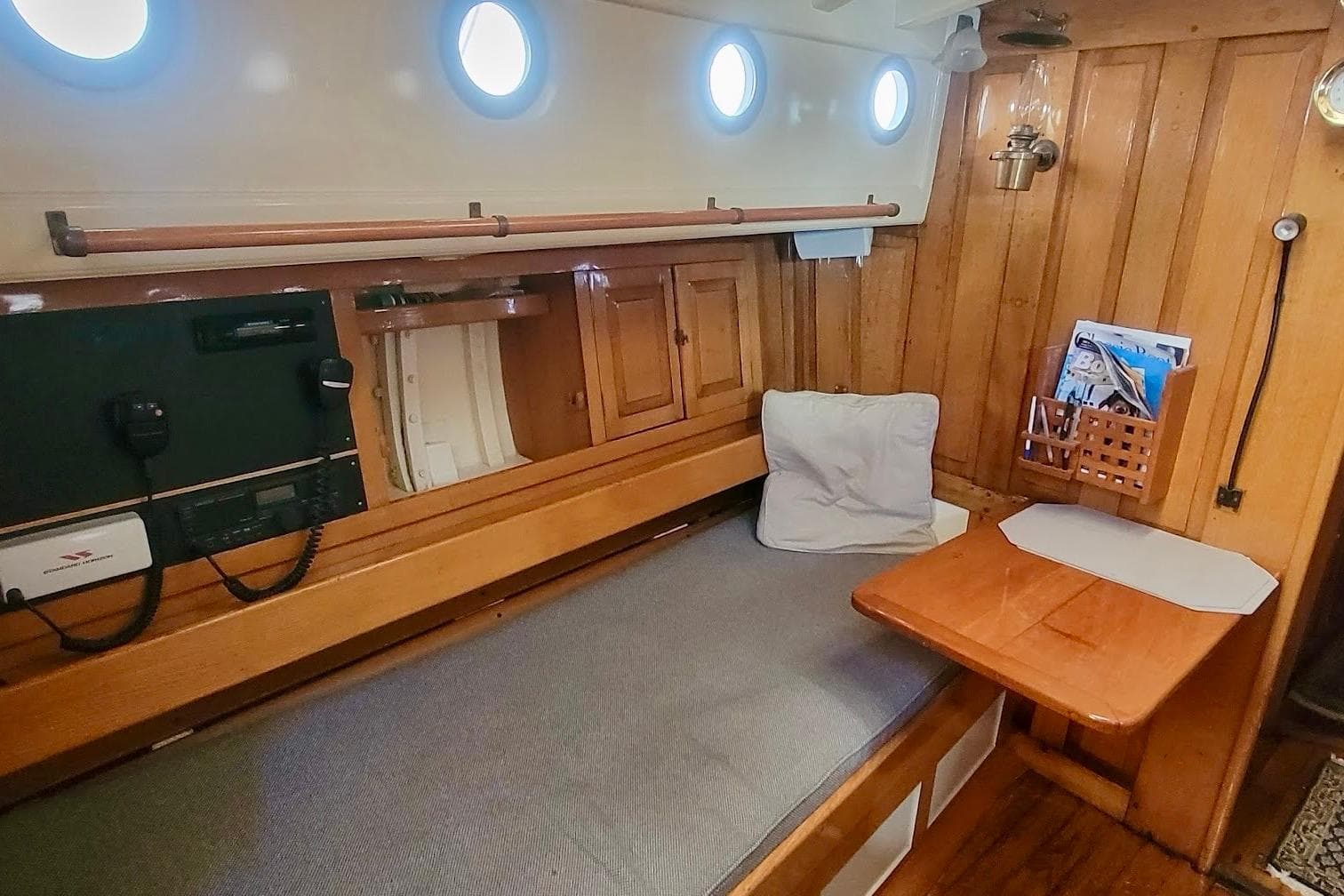 Cozy 1936 Freeman 37 boat cabin with wooden interior, portholes, and a cushioned bench.