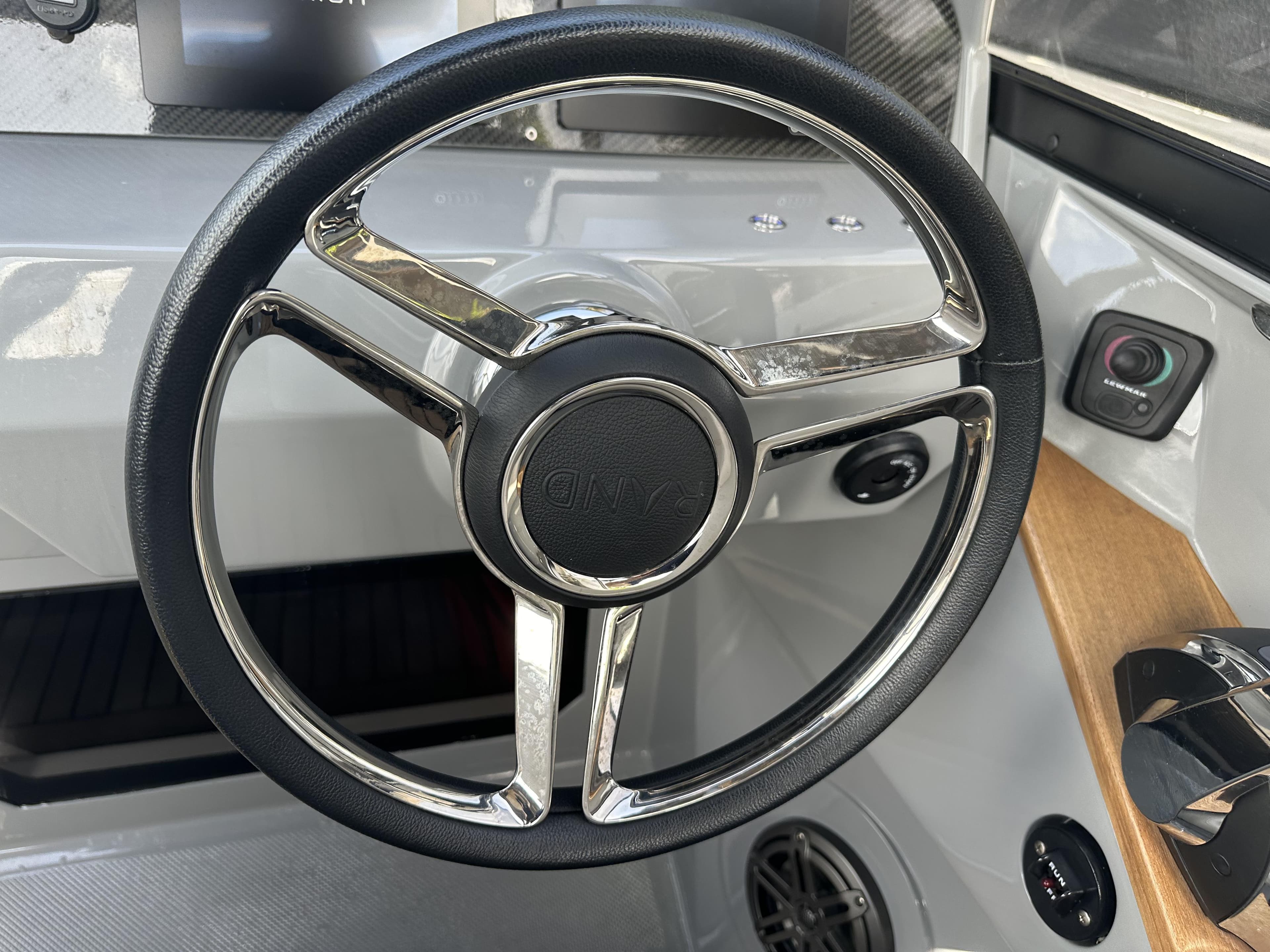 Steering wheel of a 2021 Rand Leisure boat, featuring sleek design and modern controls.