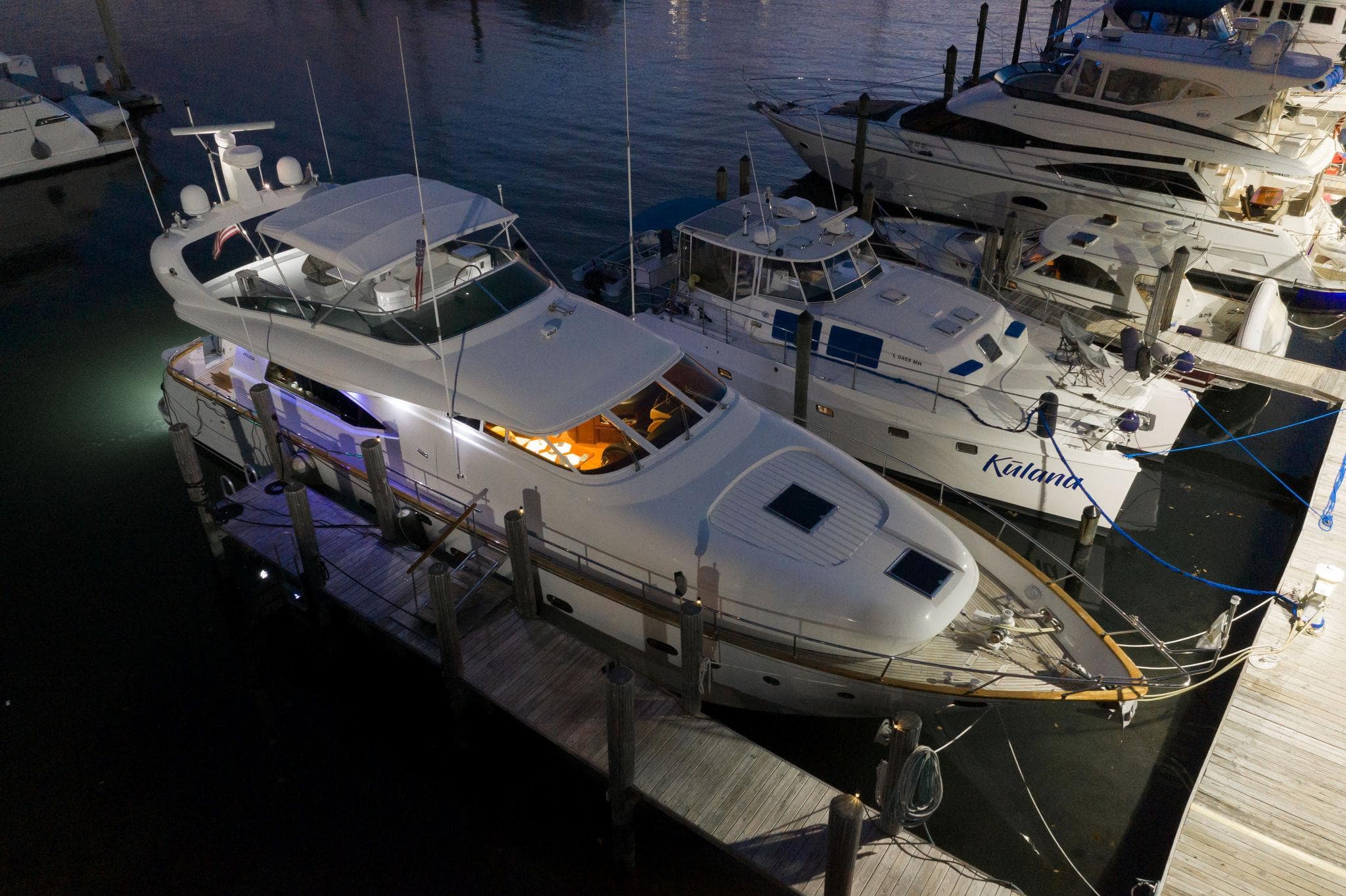 Luxurious 1997 Maiora FIPA 70' Flybridge yacht docked at night, illuminated interior.