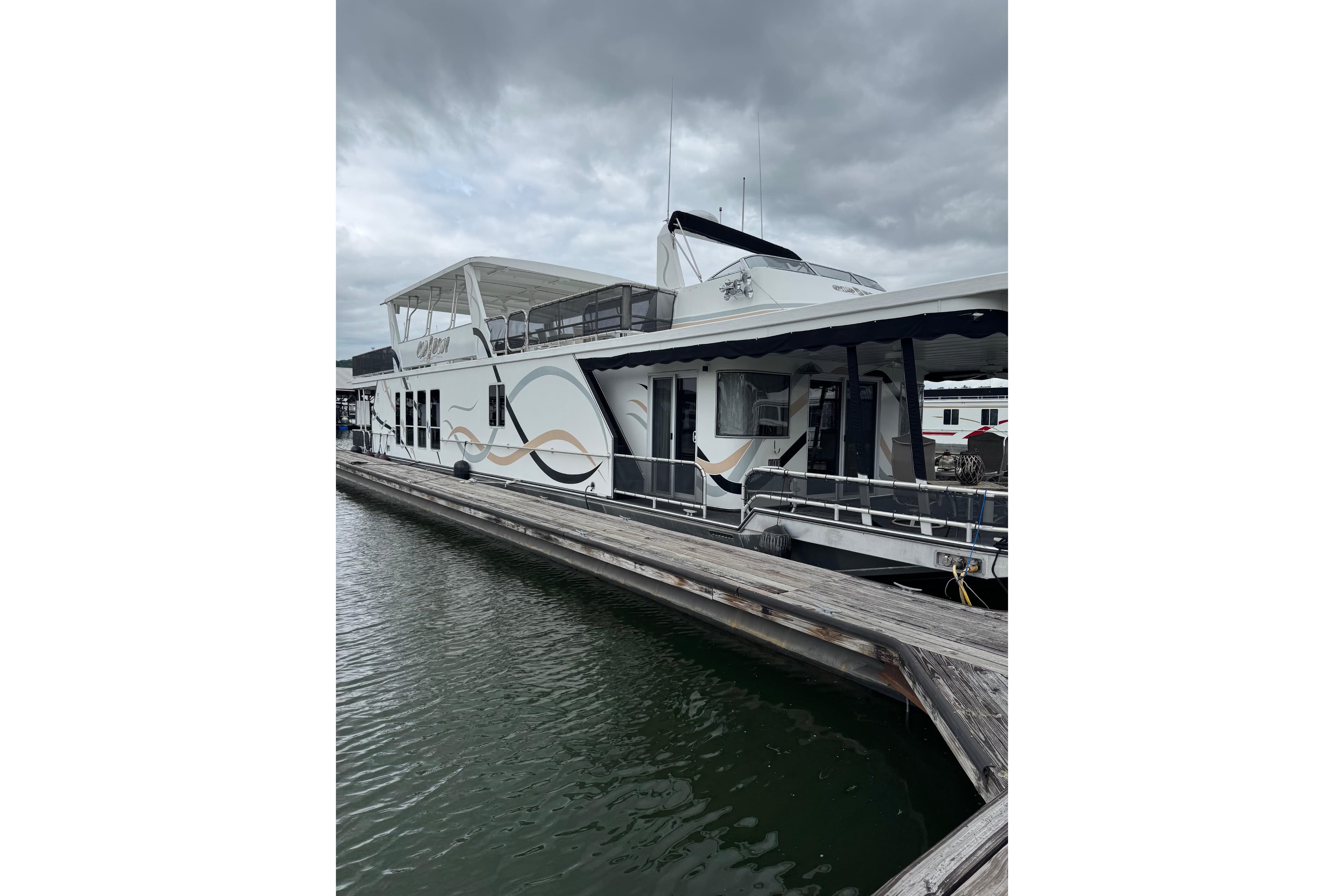 Houseboat docked at marina, Sharpe 80 X 18 model, 2001, under cloudy skies.