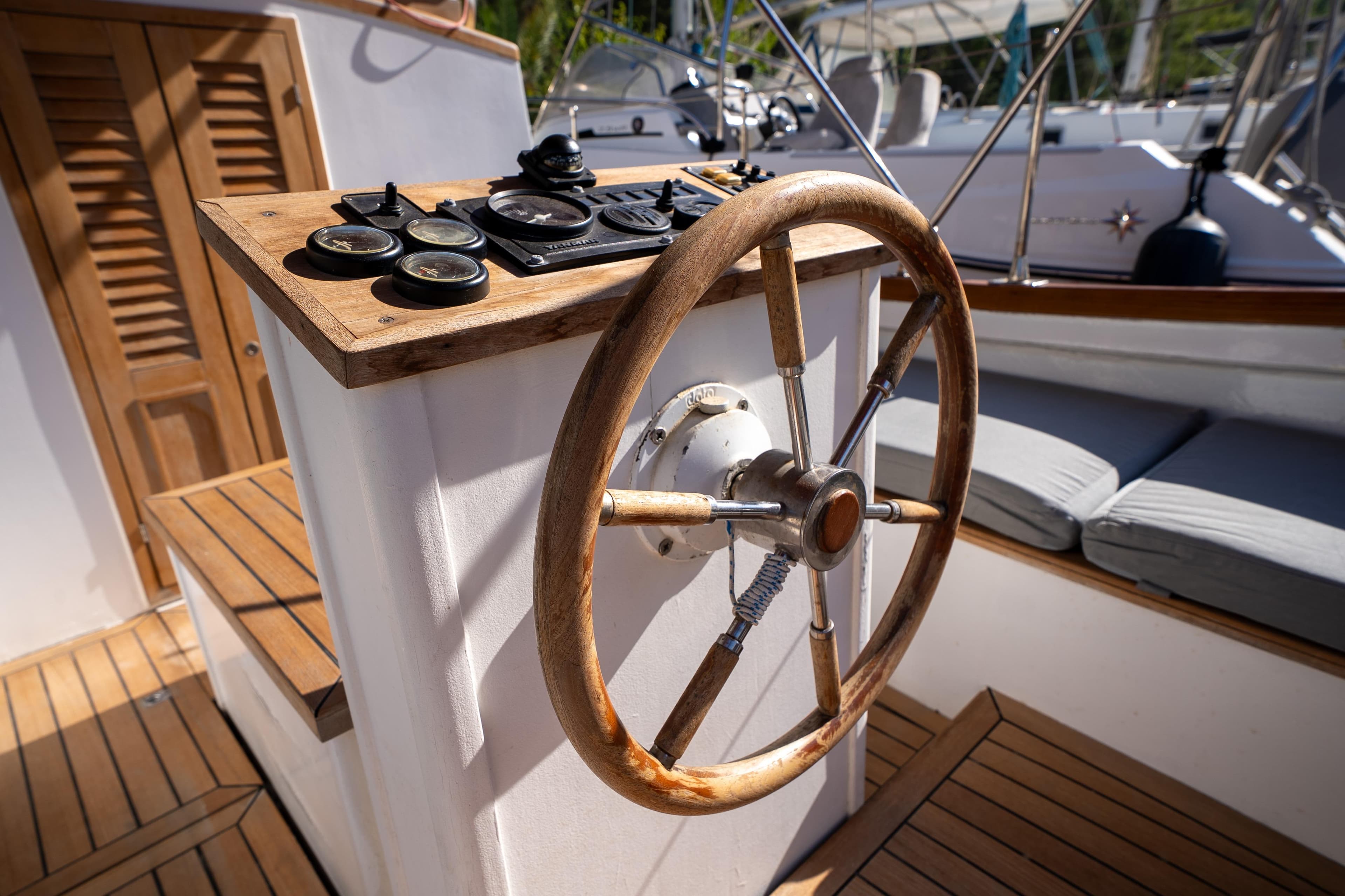 Wooden steering wheel and controls on a 1999 Custom Lykia boat deck.