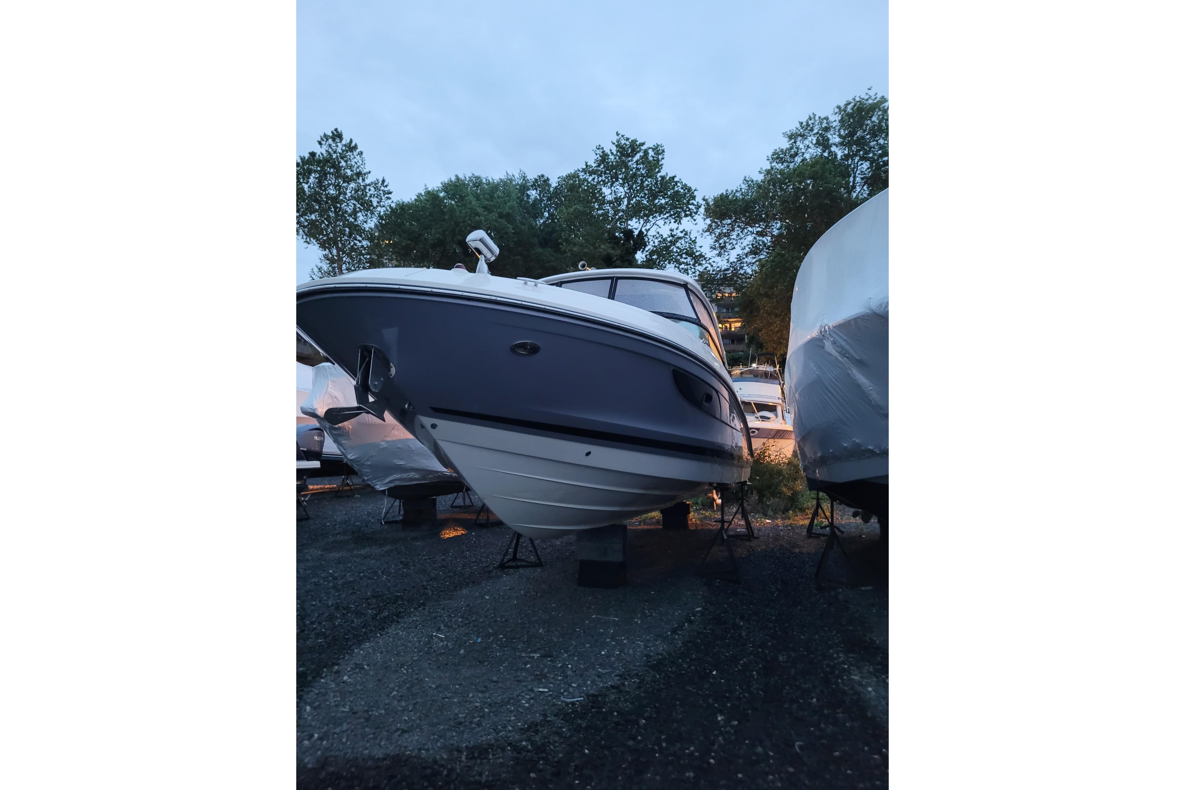 2019 Sea Ray SLX 350 Outboard boat on stands, surrounded by trees and other boats.