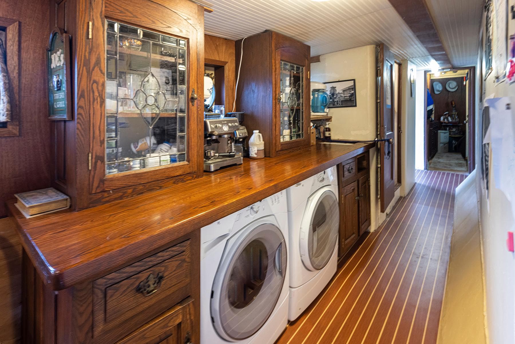 Laundry area with wooden cabinets and appliances on a 1943 Custom Navy Tug.
