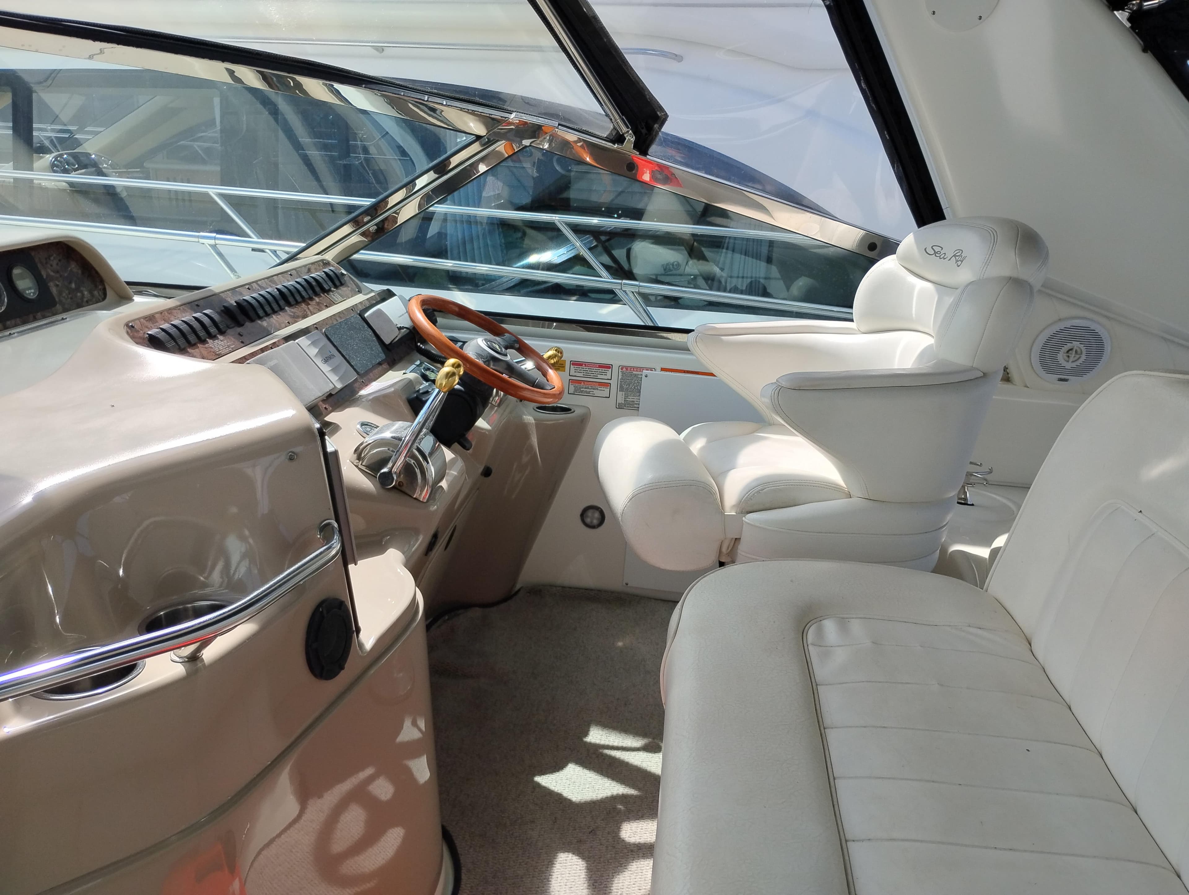 1999 Sea Ray 400 Sundancer cockpit with white leather seating and wooden steering wheel.