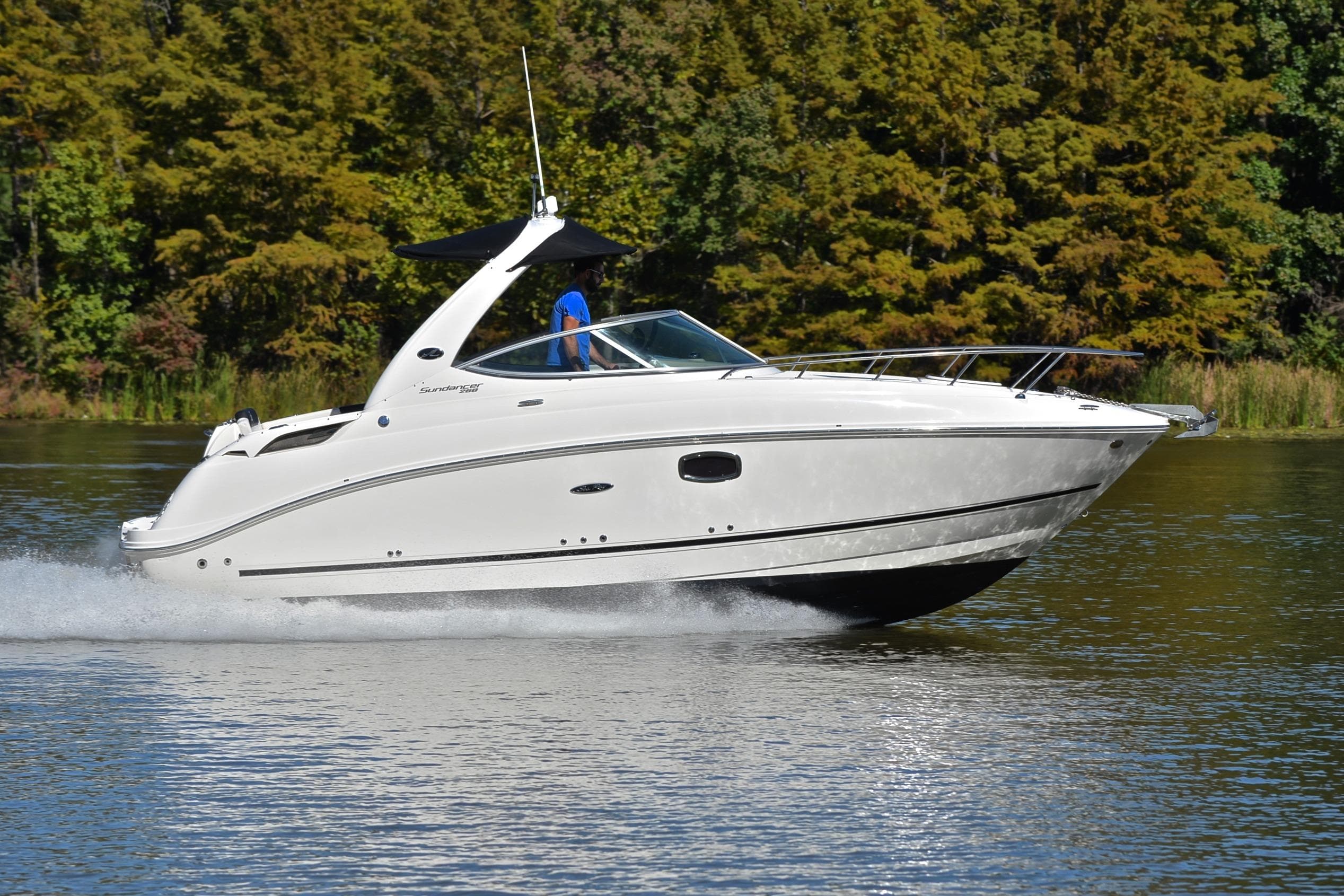 2011 Sea Ray 260 Sundancer cruising on a serene lake with lush green trees.
