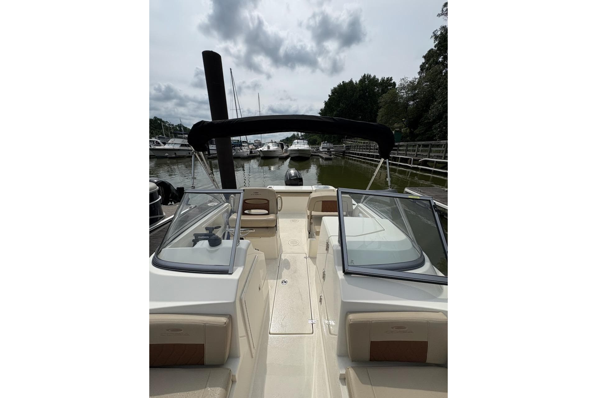 2024 Cobia 220 Dual Console boat docked, featuring sleek design and spacious seating.