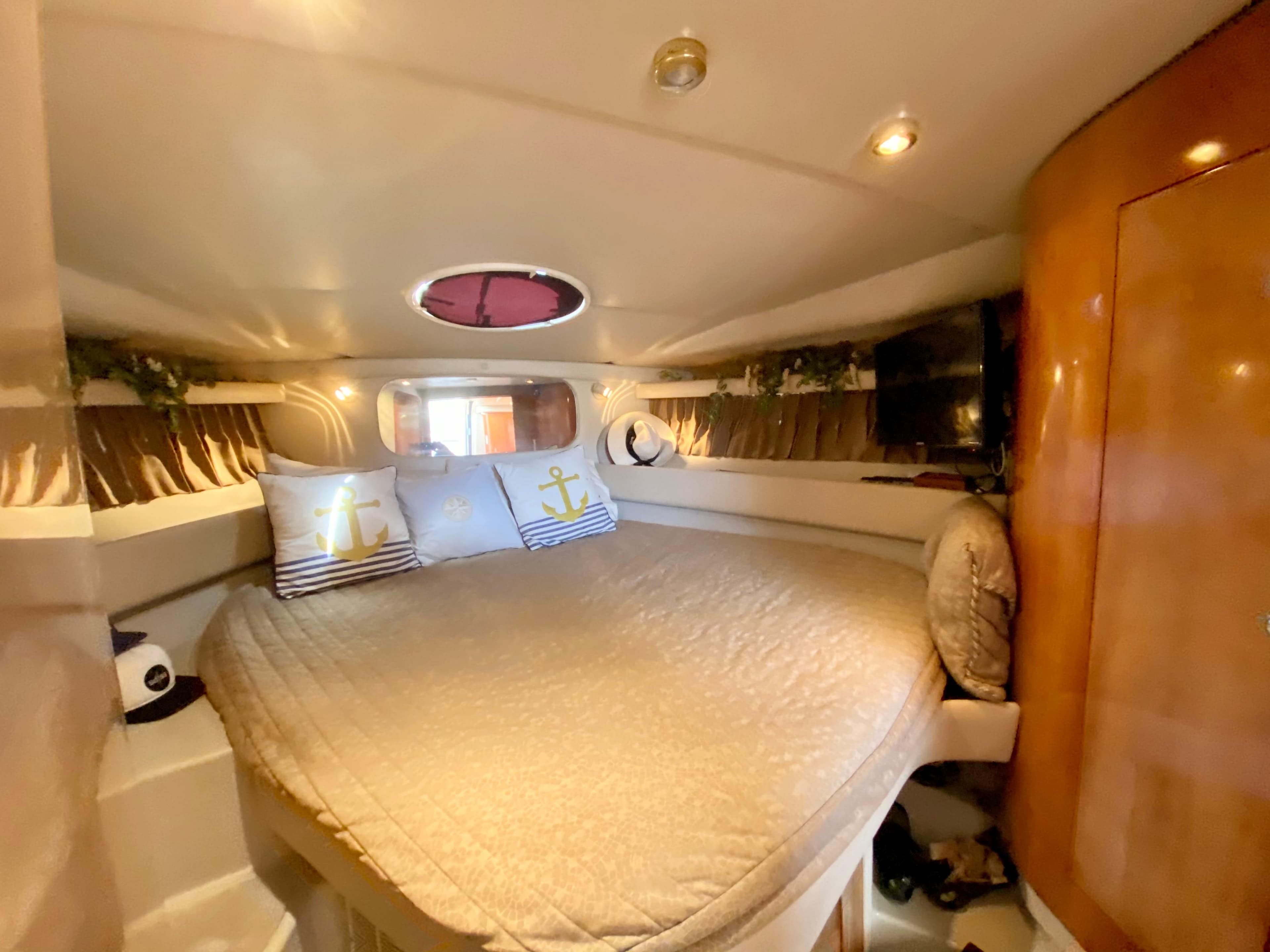Interior cabin of 2002 Regal 3860 Commodore yacht with cozy bed and nautical decor.