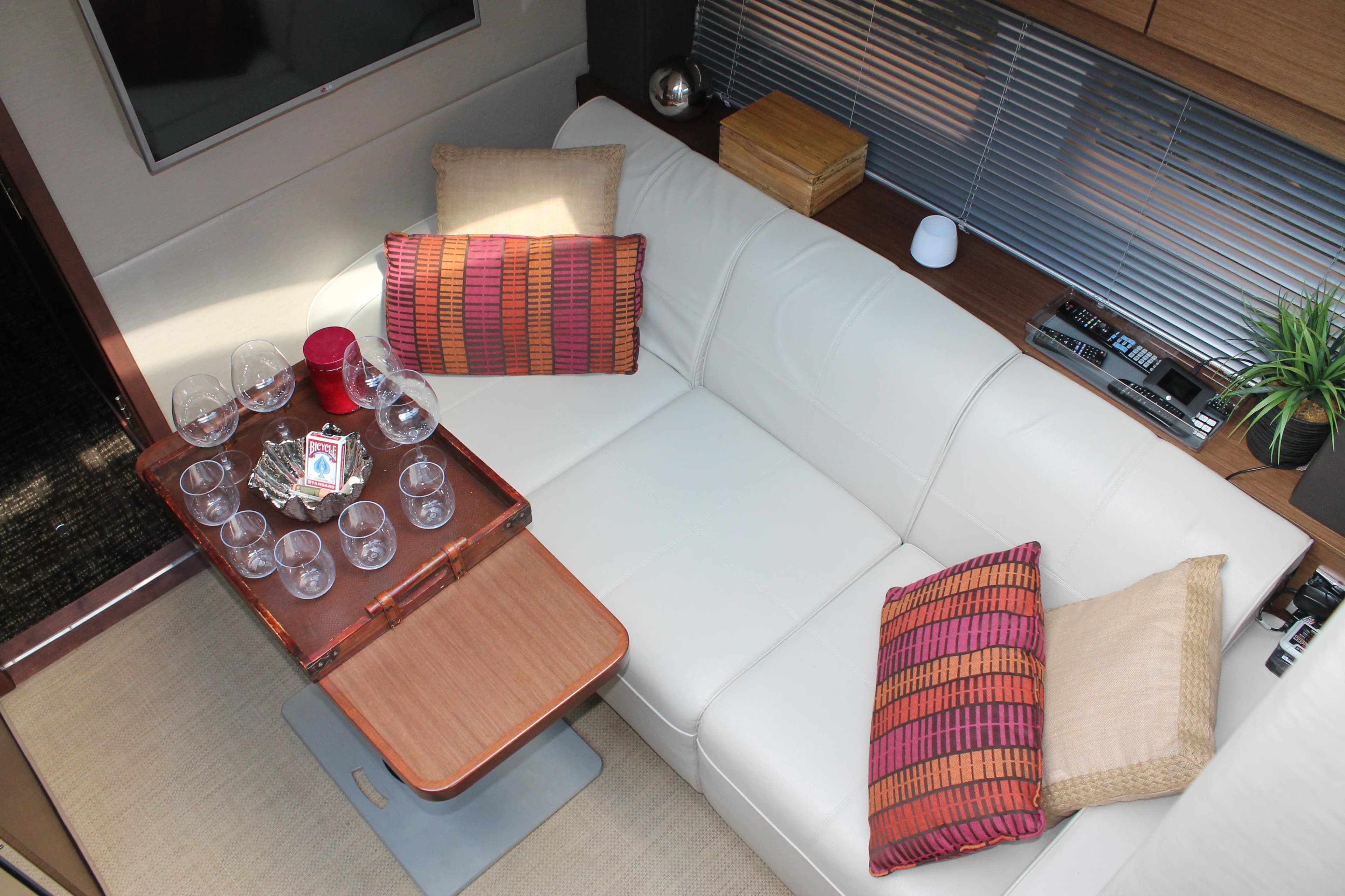 Luxurious interior of 2015 Sea Ray 470 Sundancer with white leather seating and wooden table.