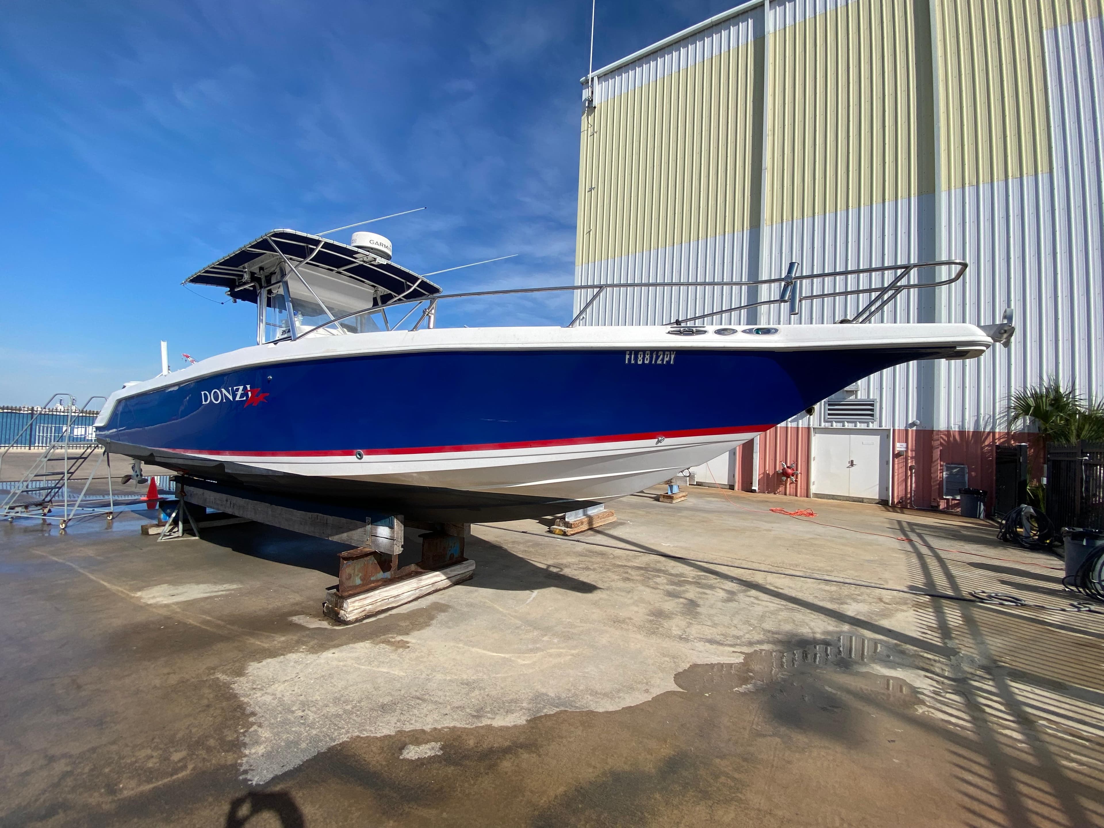2000 Donzi 35 ZF Open boat on dry dock, blue hull, sunny day.
