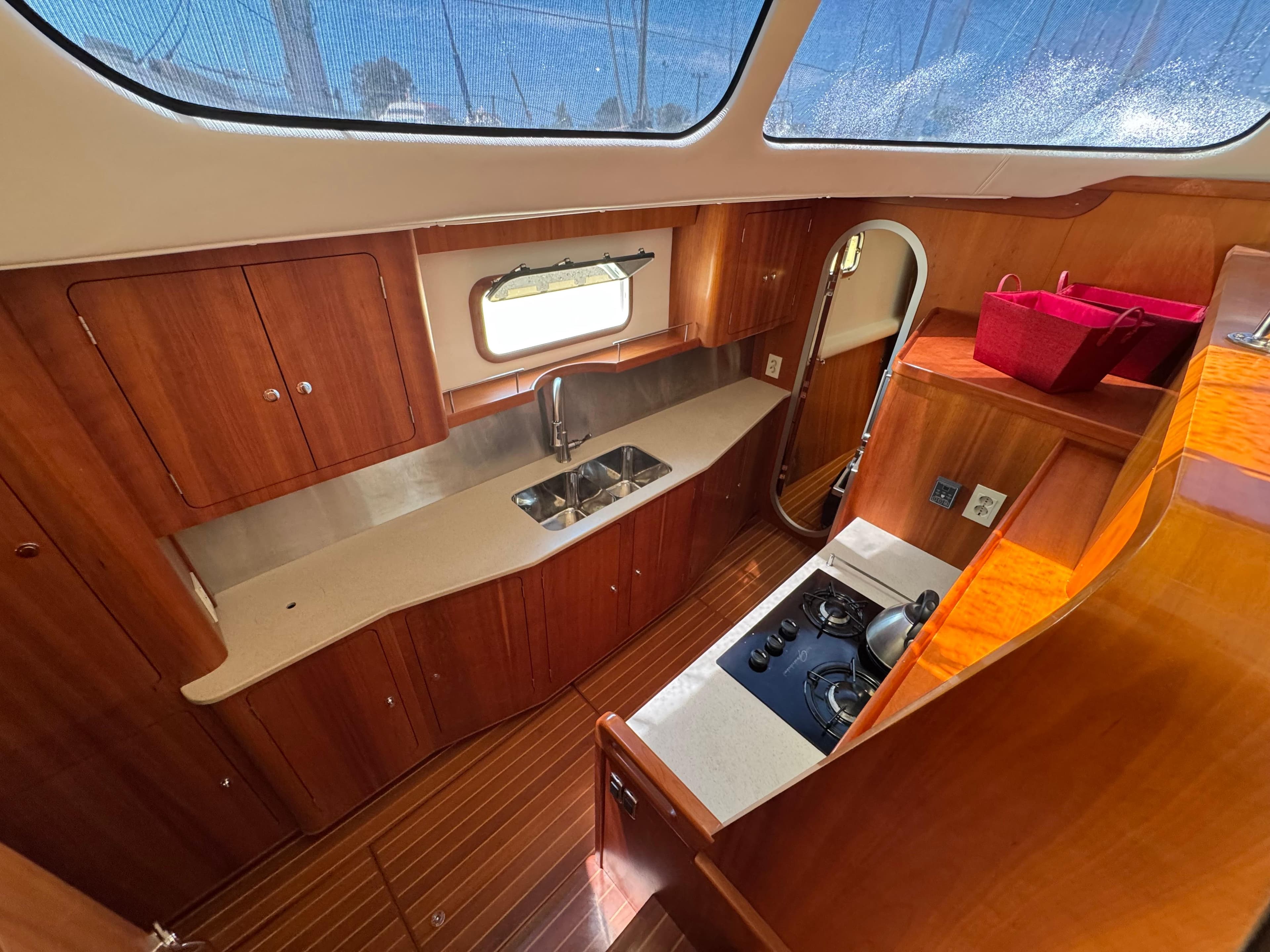 2016 Antares 44 yacht kitchen with wooden cabinetry, stainless steel sink, and stove.