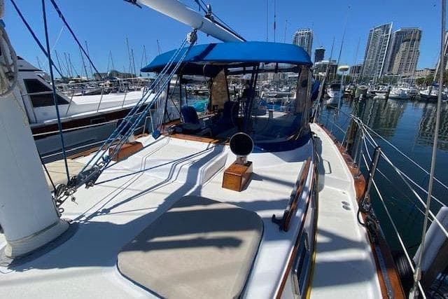 1982 Endeavour 40 sailboat docked in marina with blue canopy and city skyline.