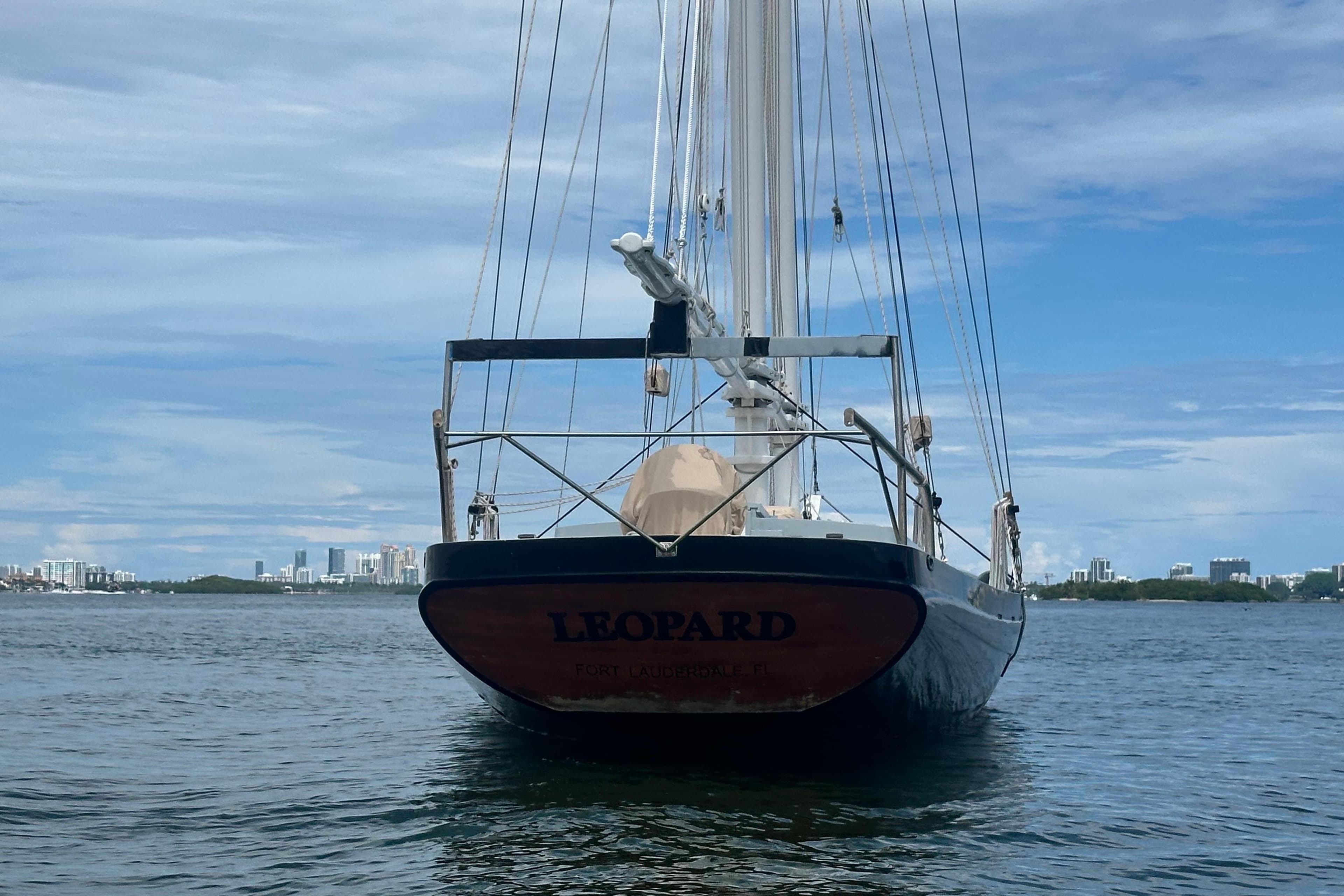 Schooner Leopard sailboat on calm water, city skyline in background, 1994 model.