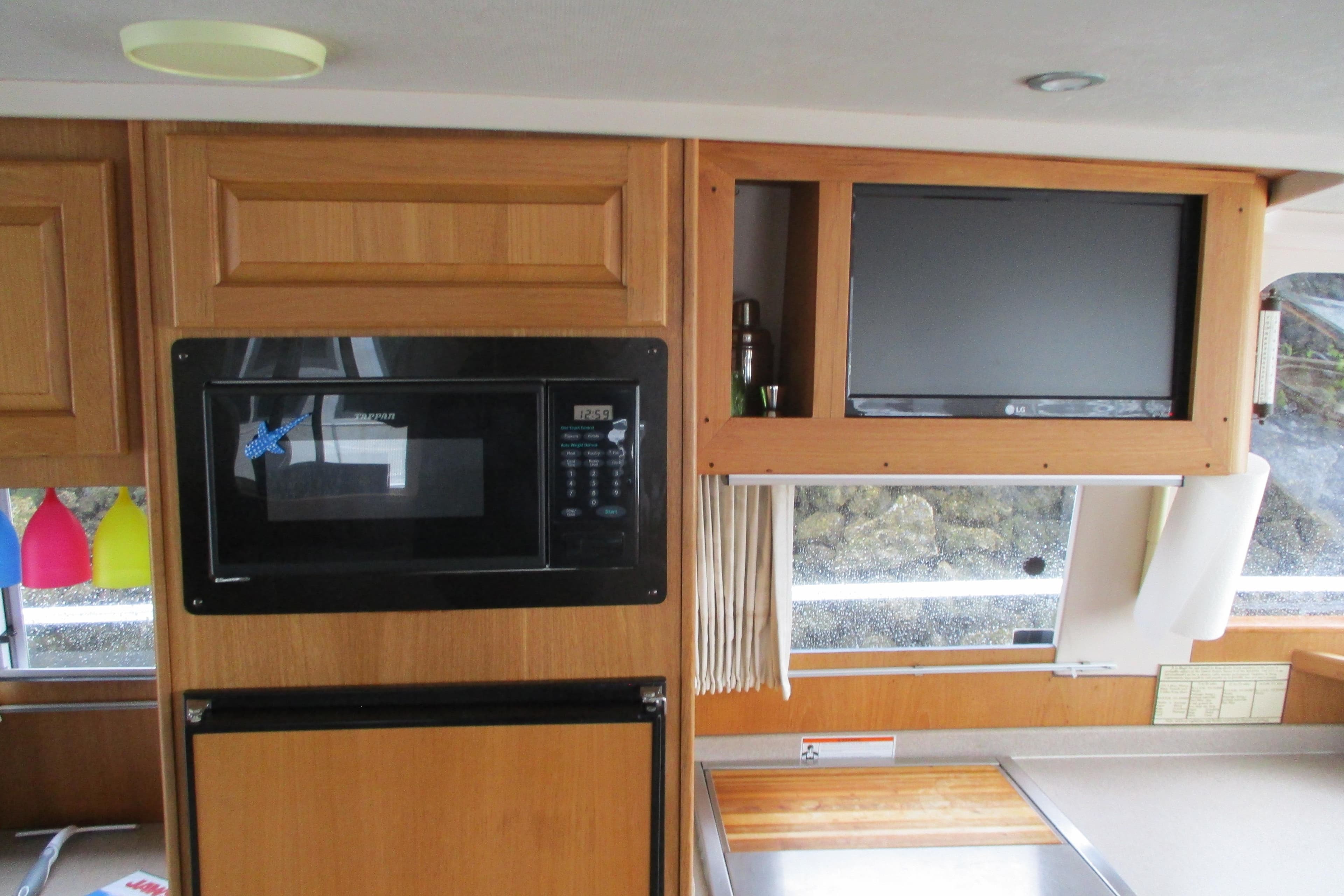Interior of 1997 Mainship 350 Trawler with microwave, TV, and wooden cabinetry.