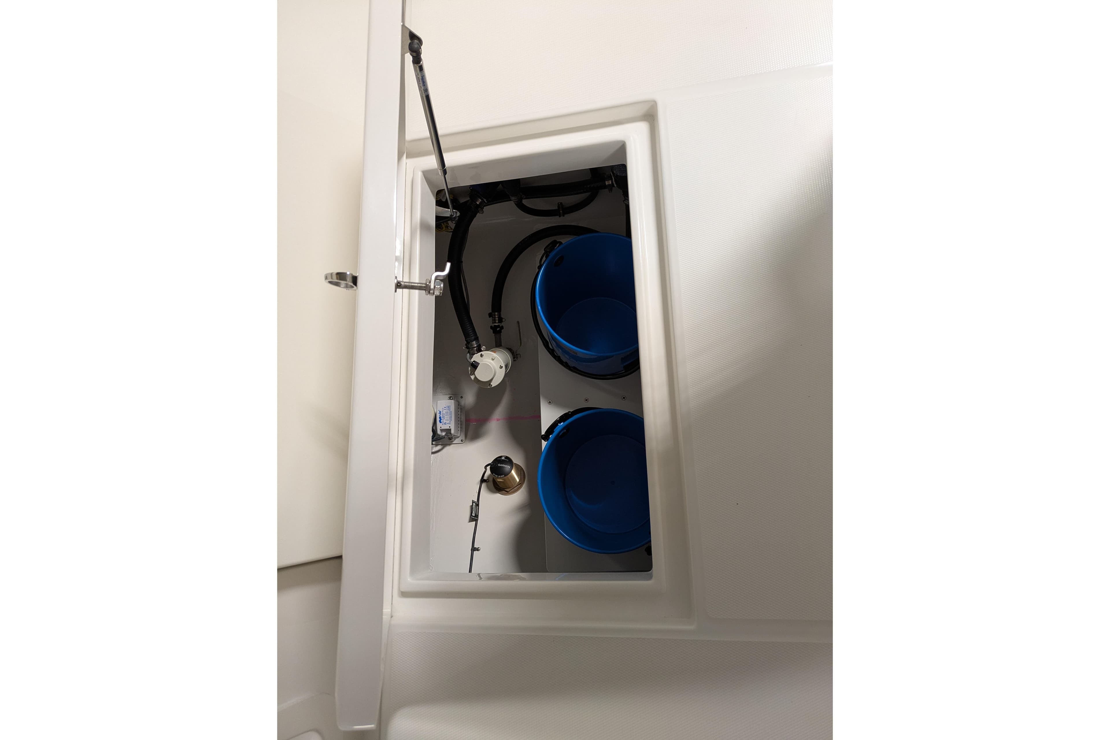 2025 Regulator 25 boat storage compartment with blue buckets and mechanical components.