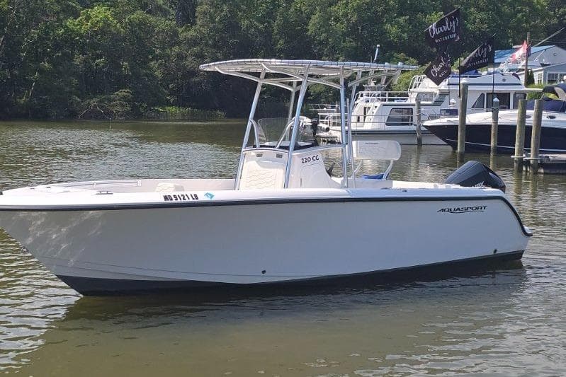 2024 Aquasport 2200 Center Console boat on calm water near docks.