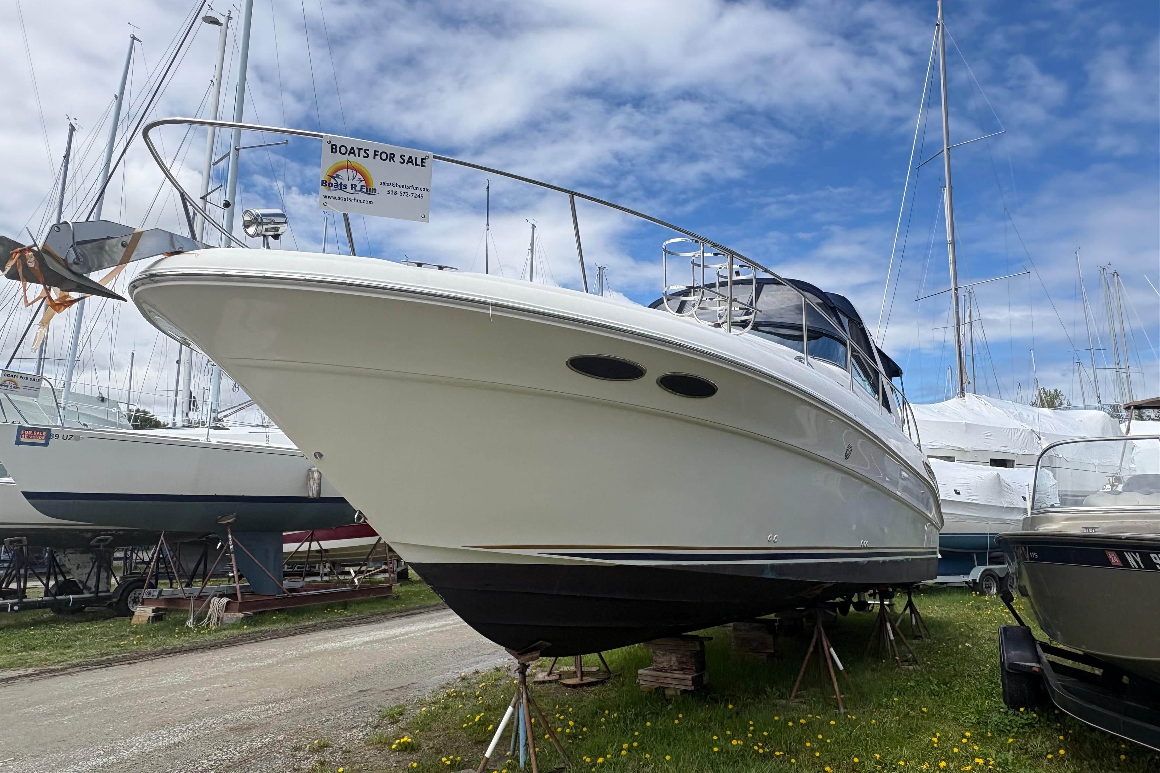 2000 Sea Ray 340 Sundancer boat for sale, displayed on land under a cloudy sky.