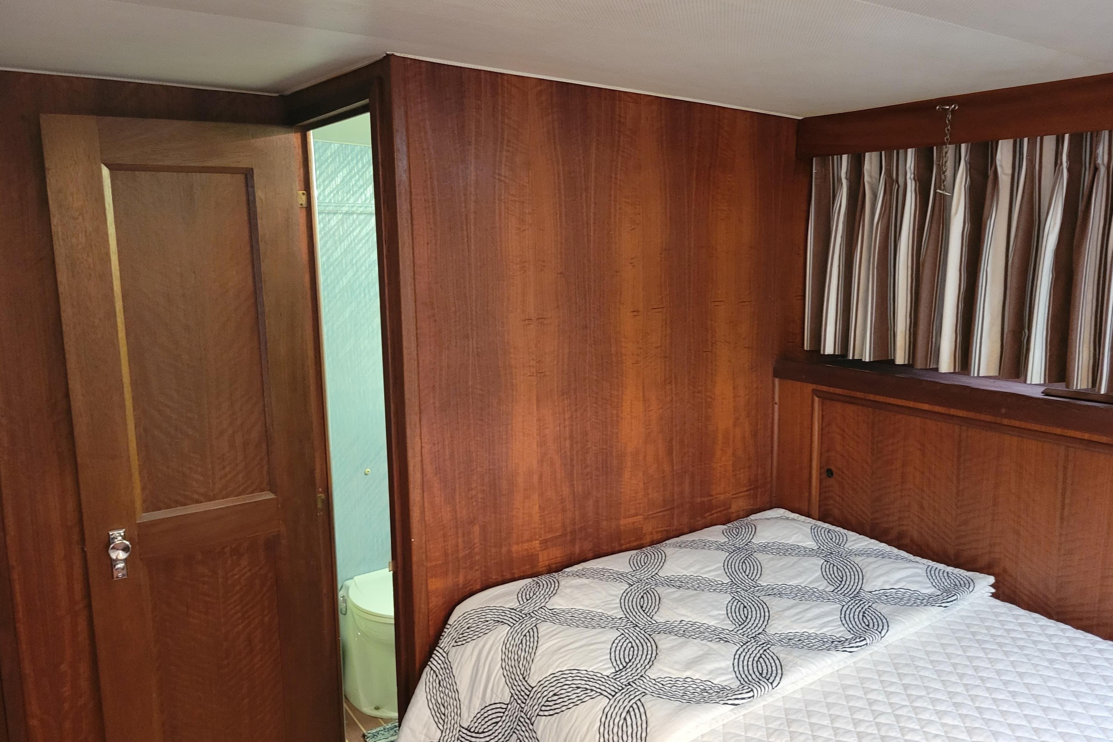 1977 Hatteras 43 Double Cabin interior with wood paneling and bed, adjacent bathroom.