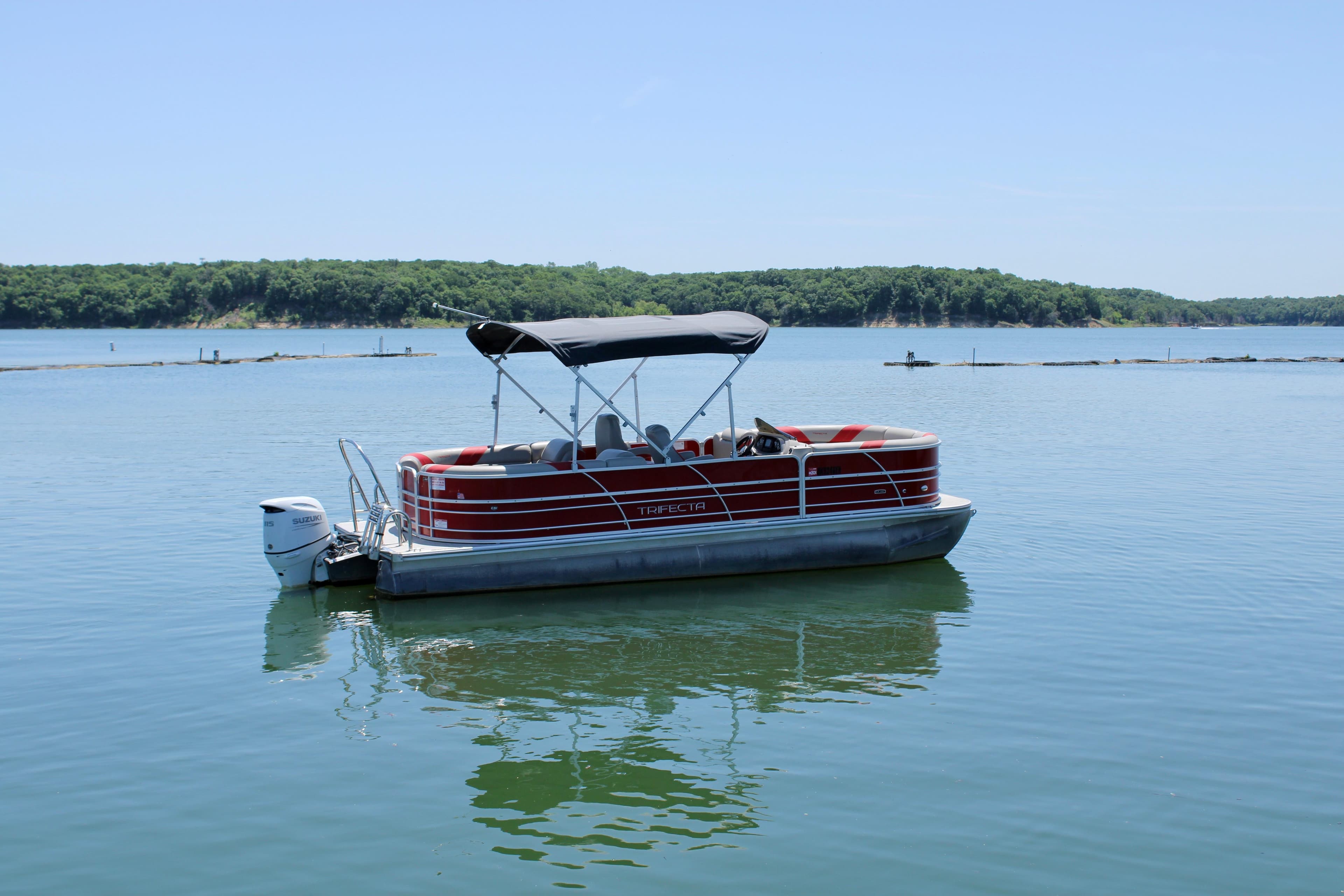 2022 Trifecta 24RFLE pontoon boat on a calm lake with scenic background.