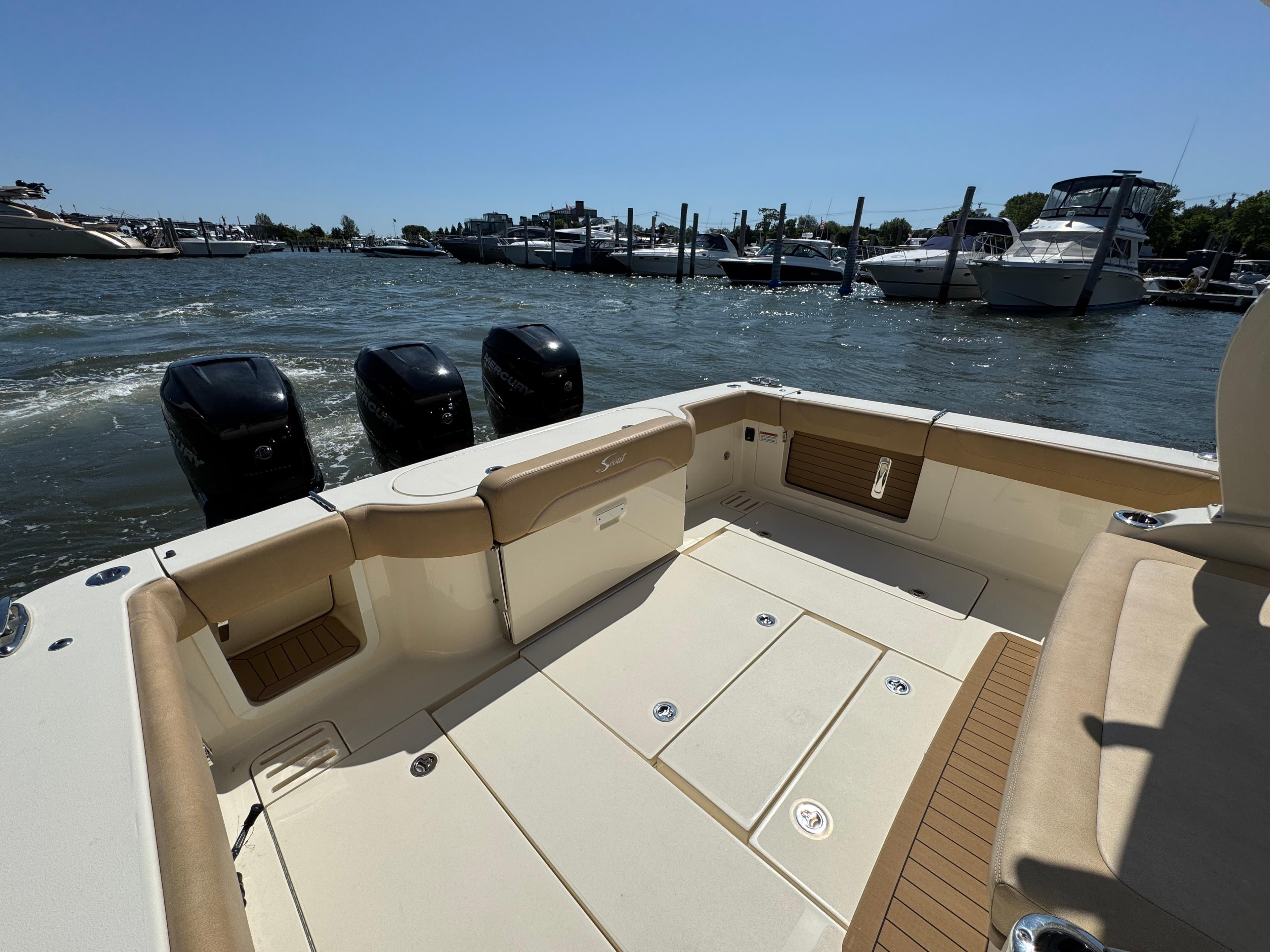 2018 Scout 380 LXF boat with triple outboard engines docked at marina.