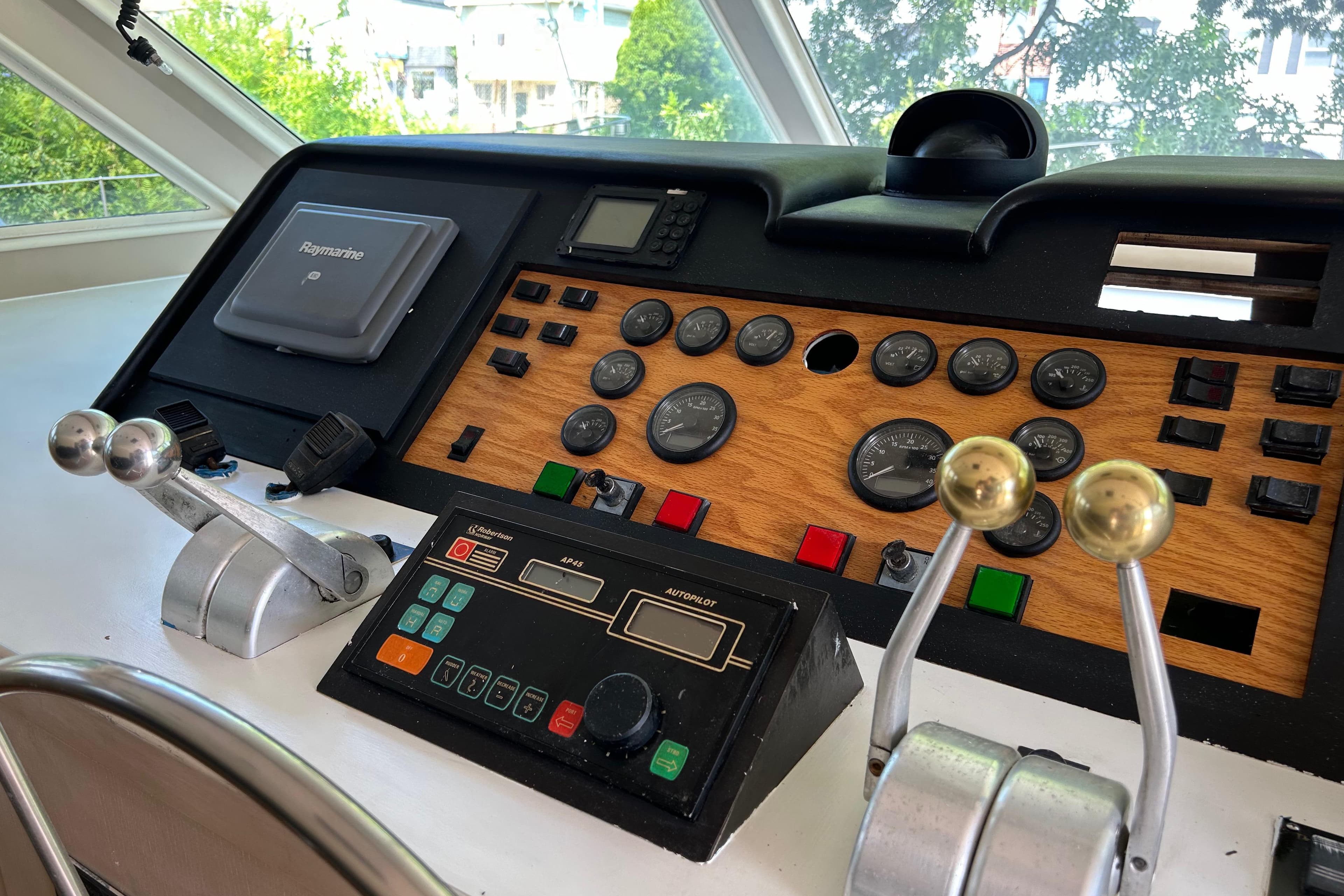 Control panel of a 1991 Hatteras Cockpit Motor Yacht with gauges and levers.