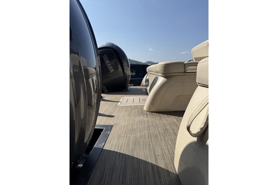 2021 Bennington 27 QXSBWA X2 boat deck with Yamaha engine, beige seating, and clear sky.