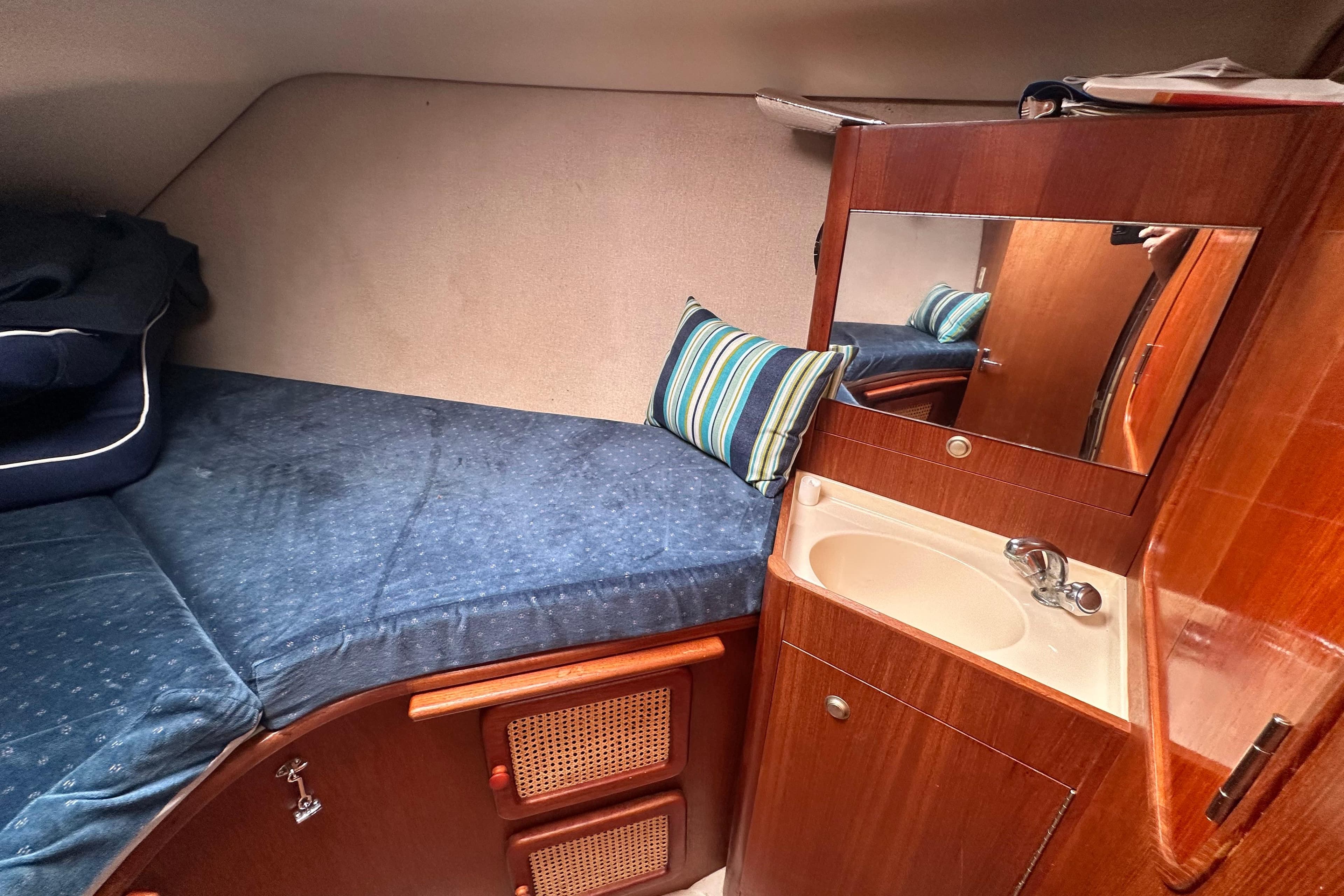 1997 Hunter 376 yacht interior with blue bedding, striped pillow, and wooden cabinetry.