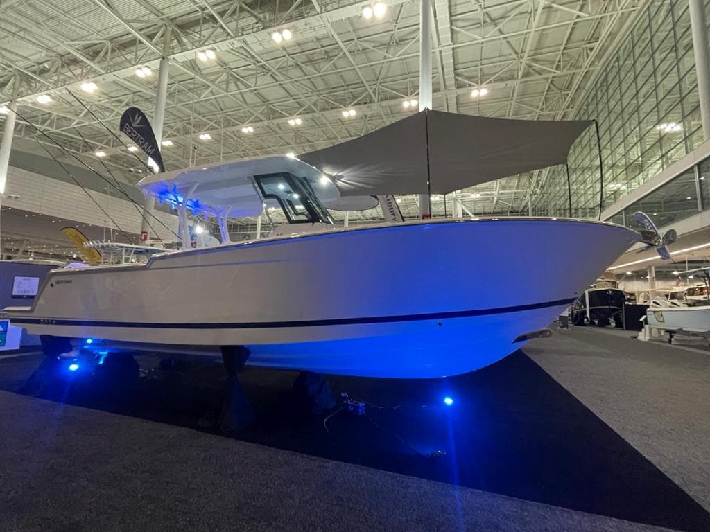 2023 Bertram 28 CC boat displayed at an indoor boat show with blue accent lighting.