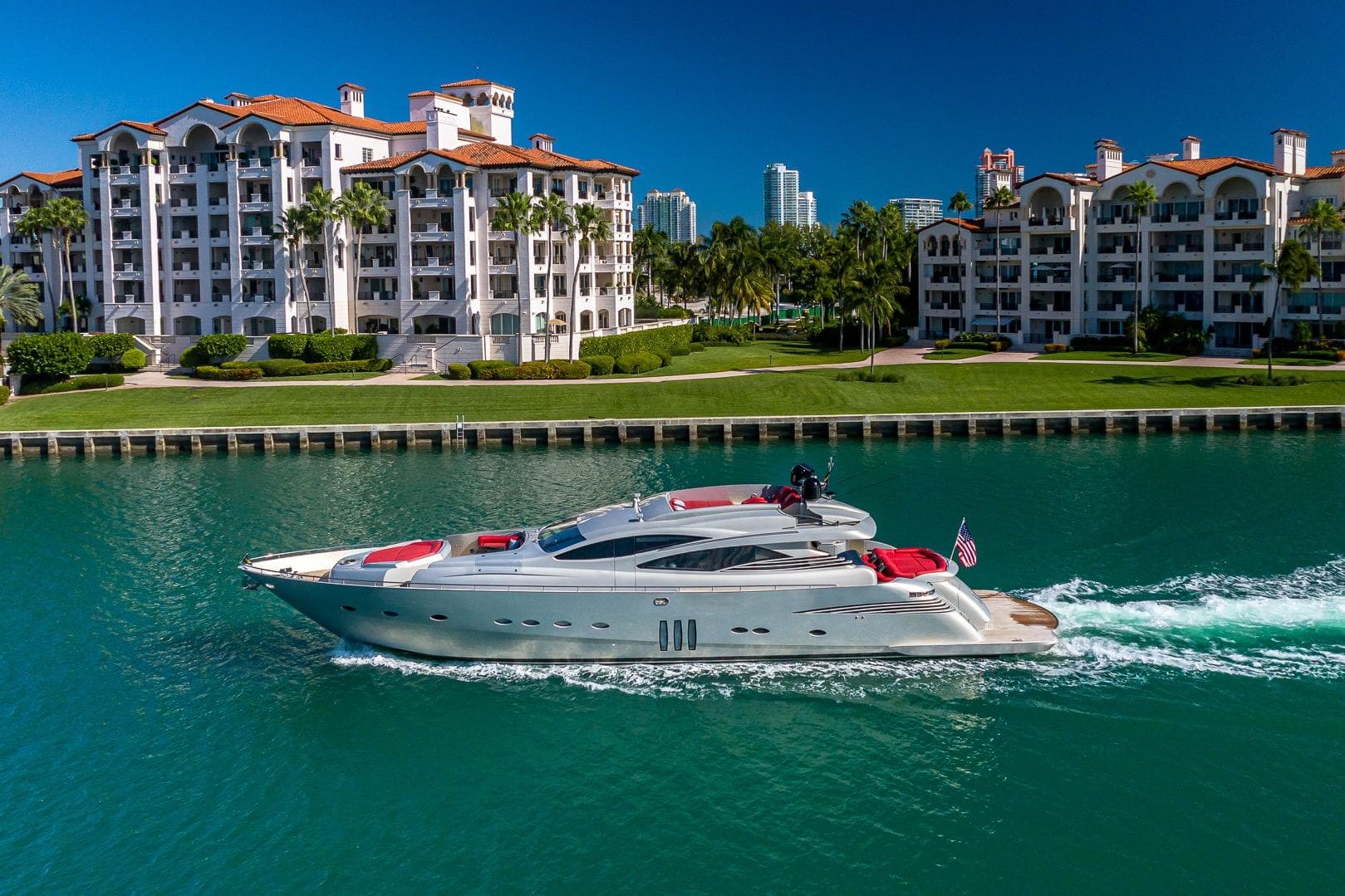 Luxurious 2008 Pershing 90 yacht cruising near waterfront residences under clear blue skies.
