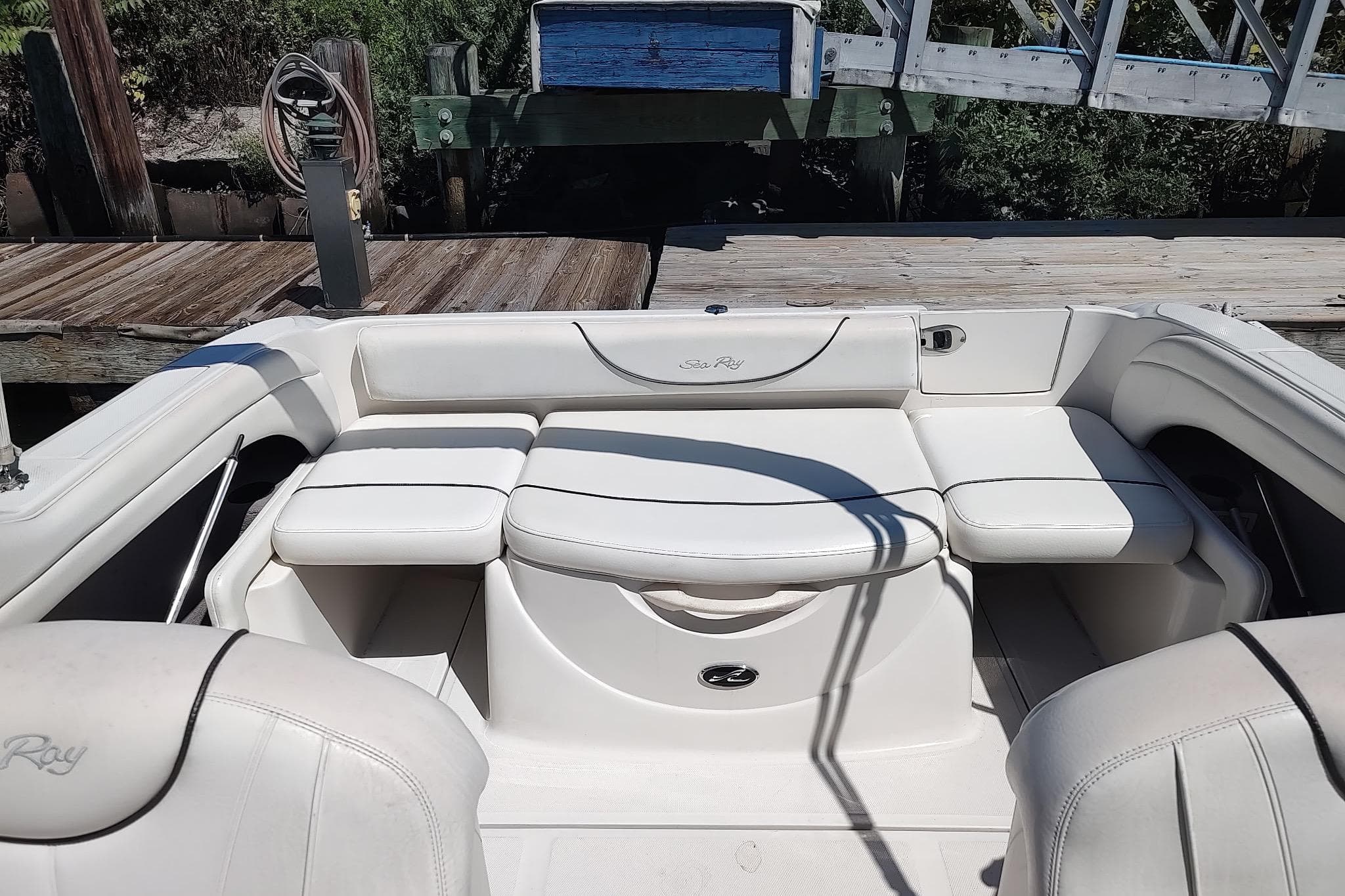 2004 Sea Ray 215 Weekender boat interior with white seating and dock background.
